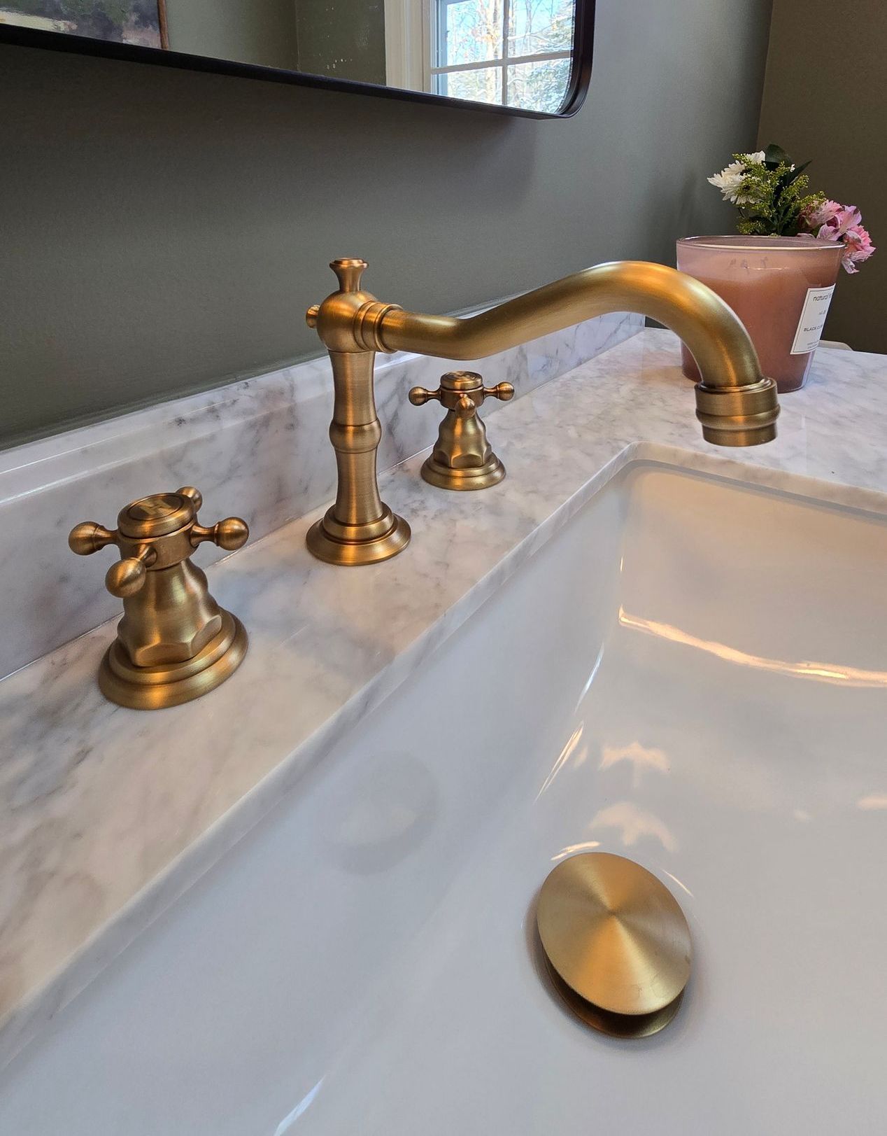A bathroom sink with a brass faucet and a drain.
