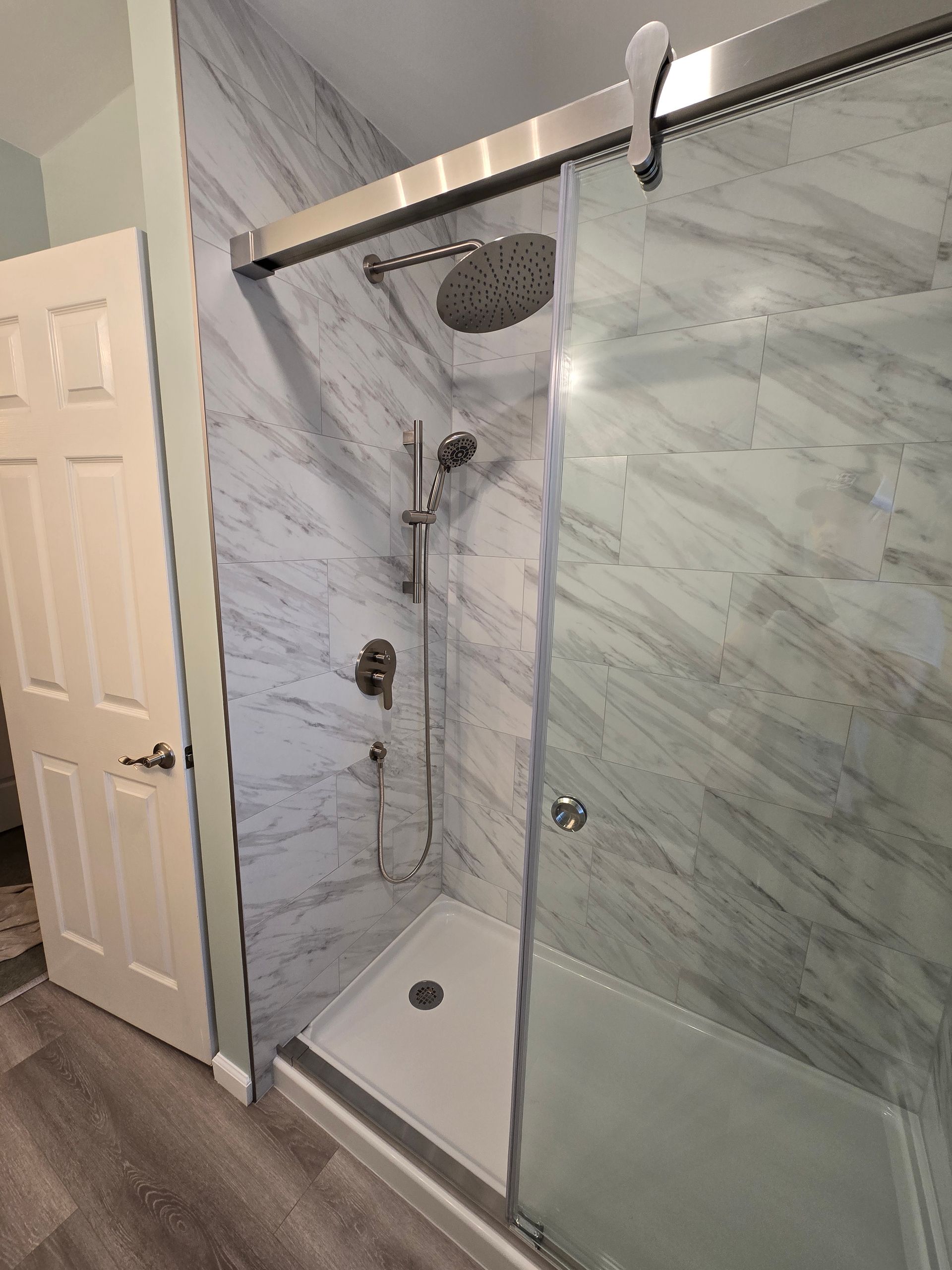 A bathroom with a walk in shower and marble walls.