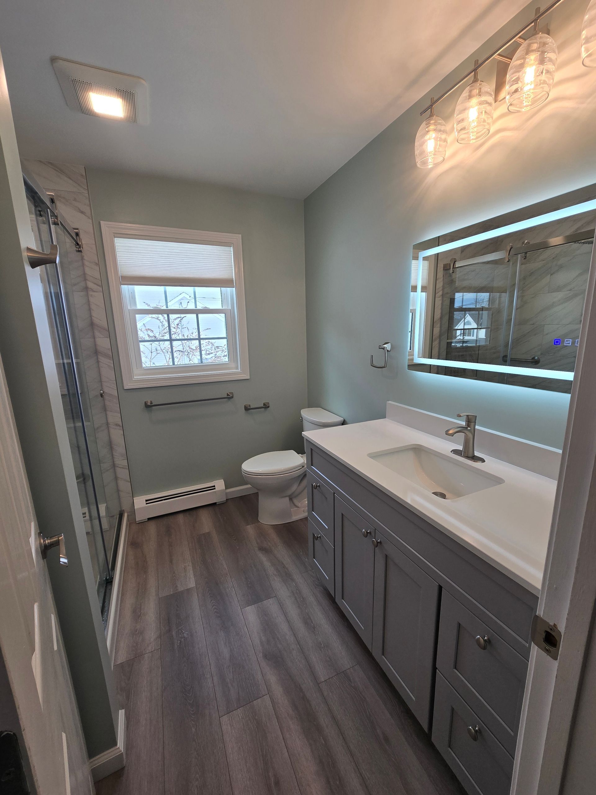 A bathroom with a sink , toilet , shower and mirror.