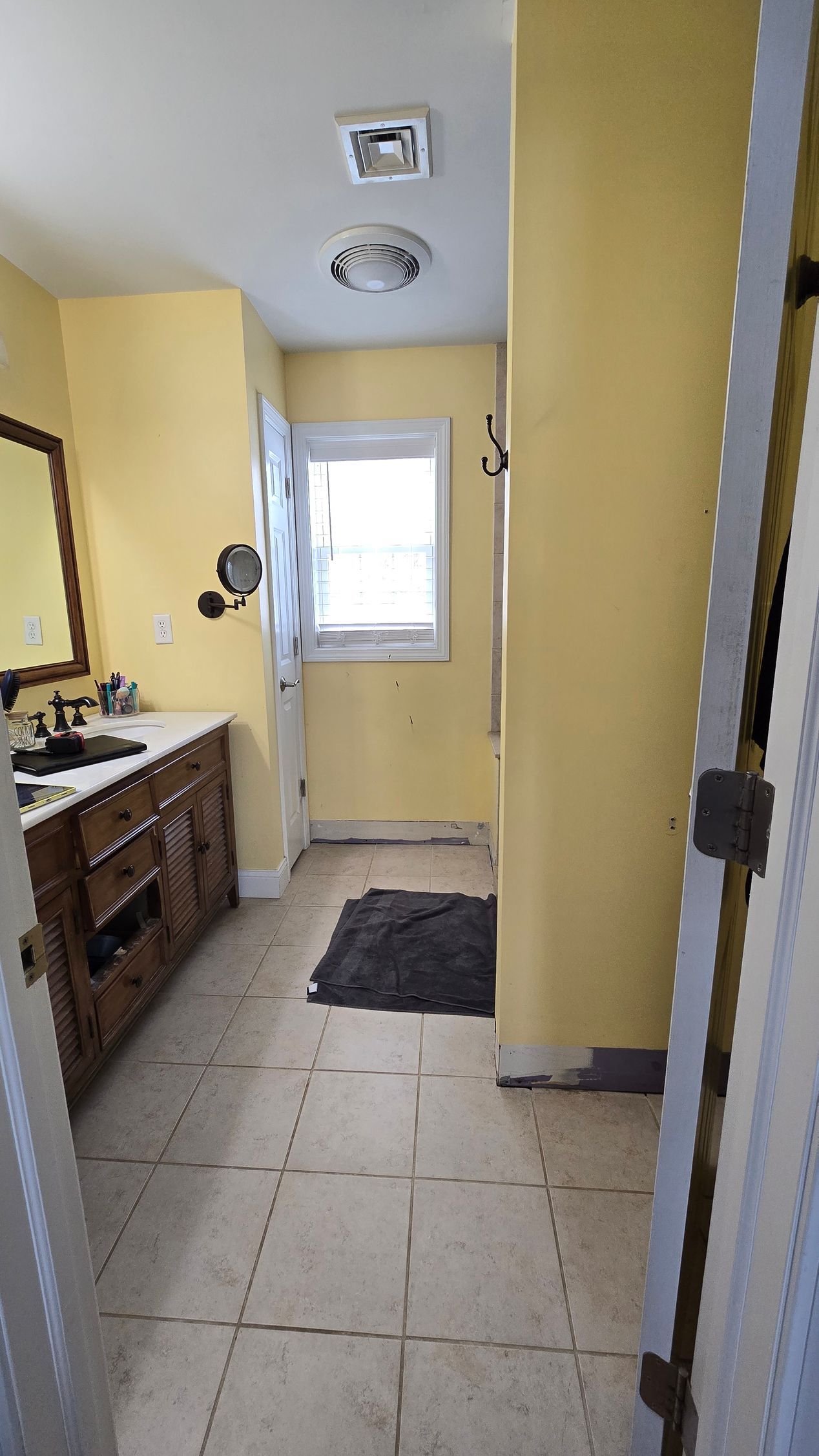 A bathroom with a walk in shower with a wooden wall and marble tiles.