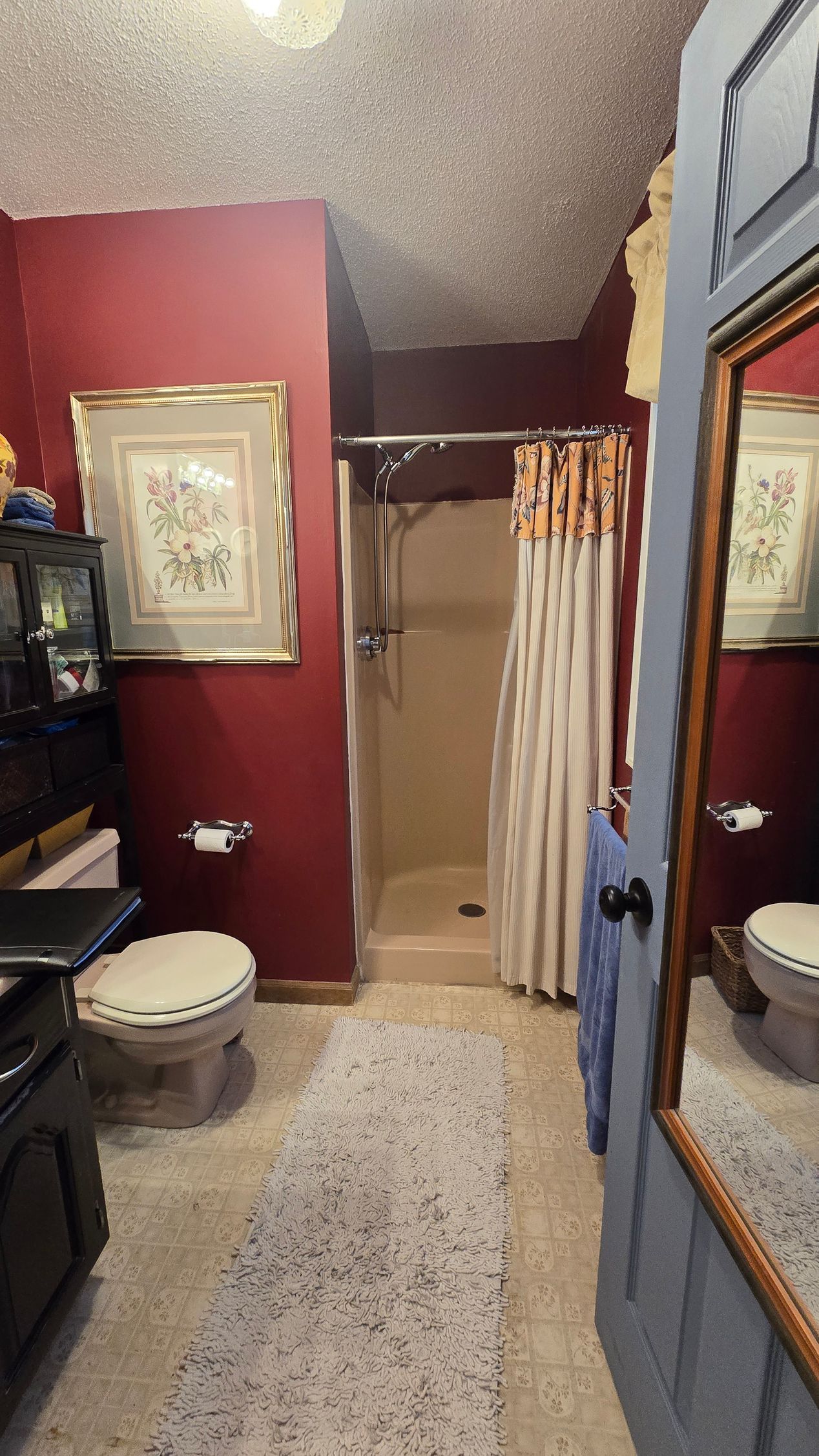 A bathroom with a toilet , sink , shower and mirror.