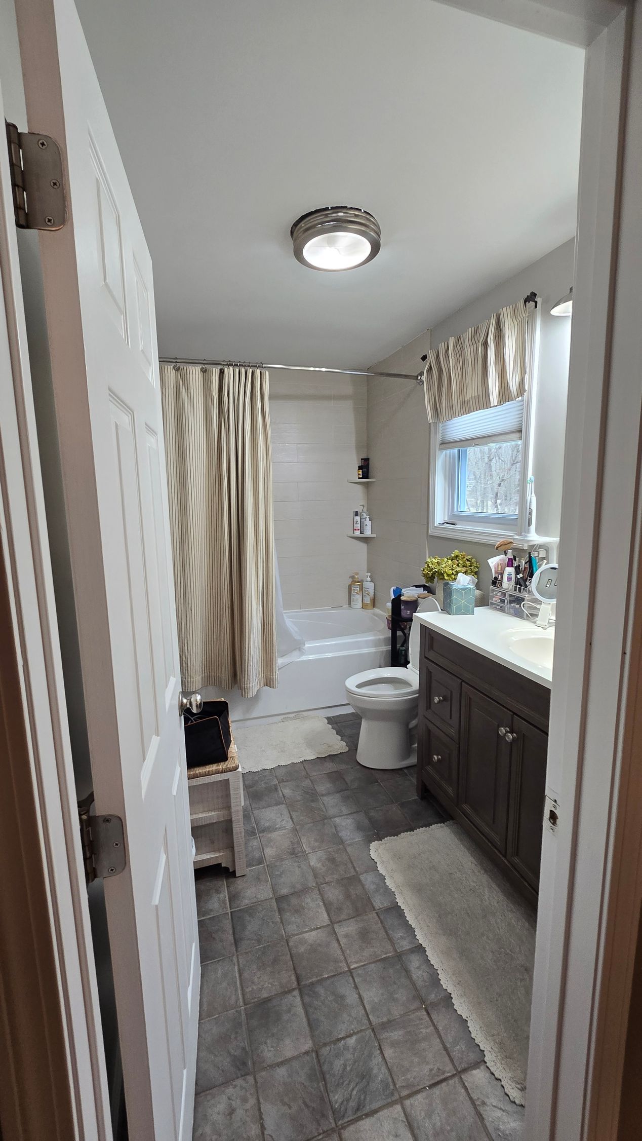 The before Bathroom remodel in Wolcott, CT with a tub, toilet, vanity, and closed door.