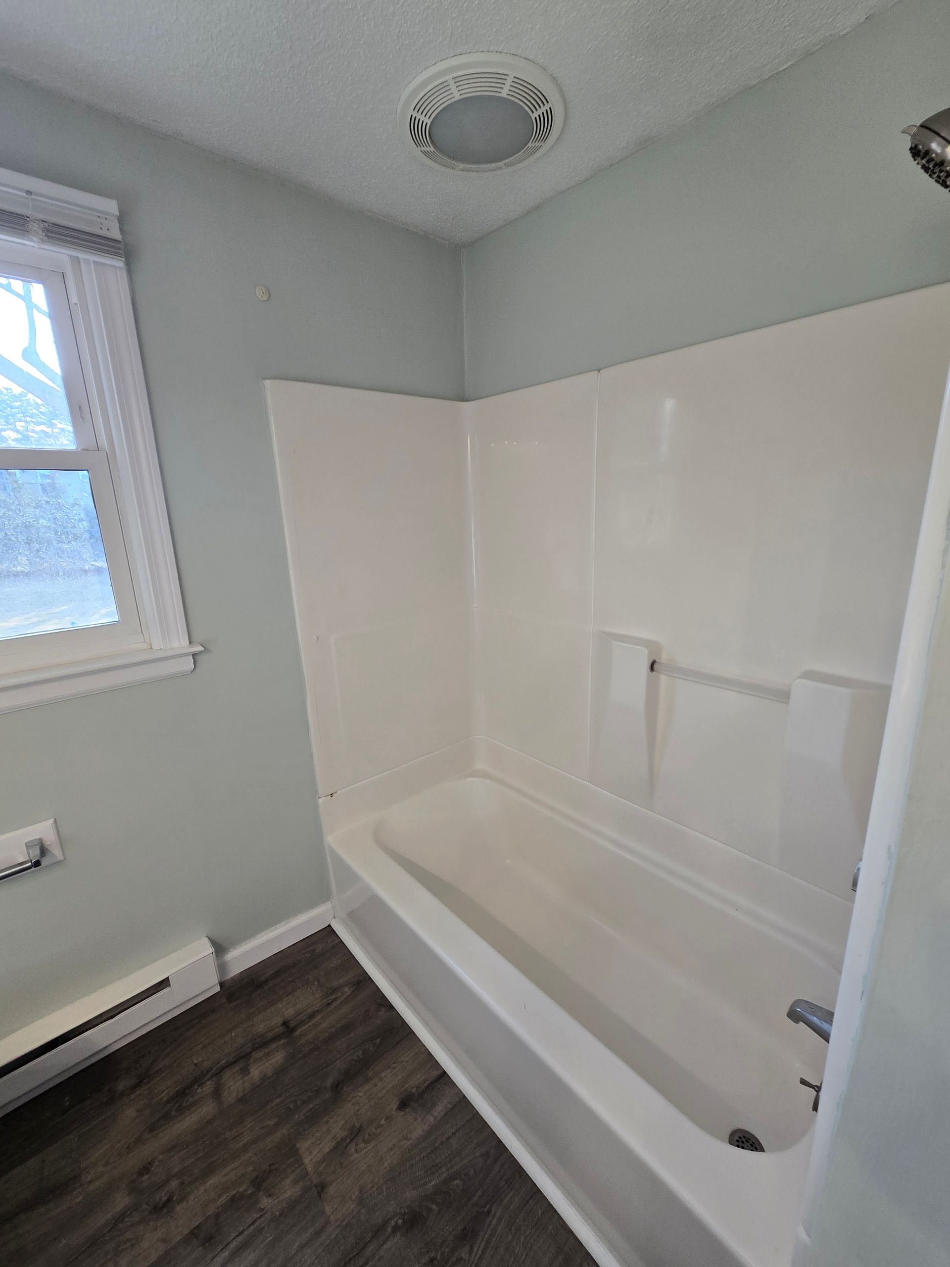 A bathroom with a bathtub and a window.