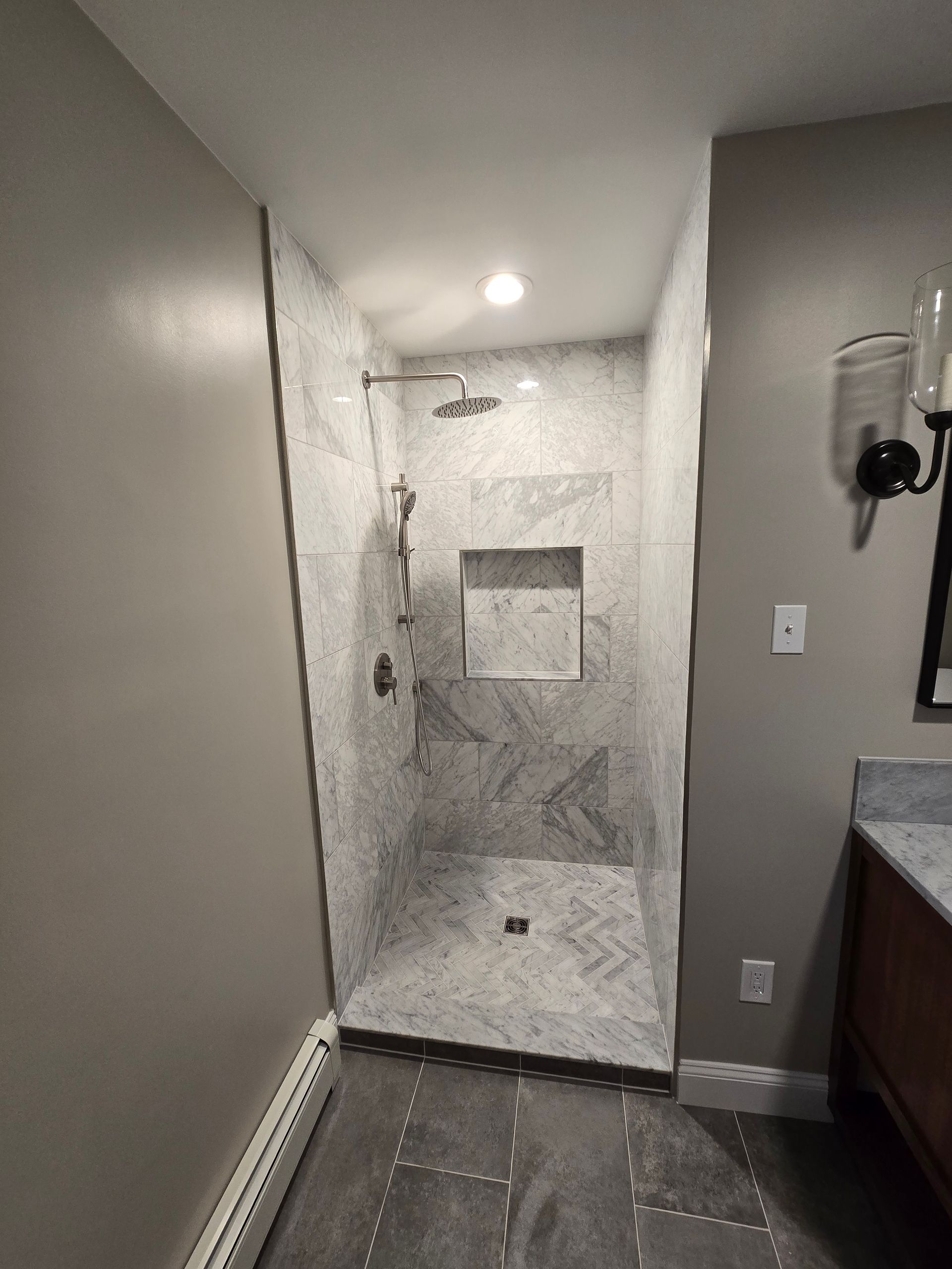 A bathroom with a shower , toilet , sink and mirror.