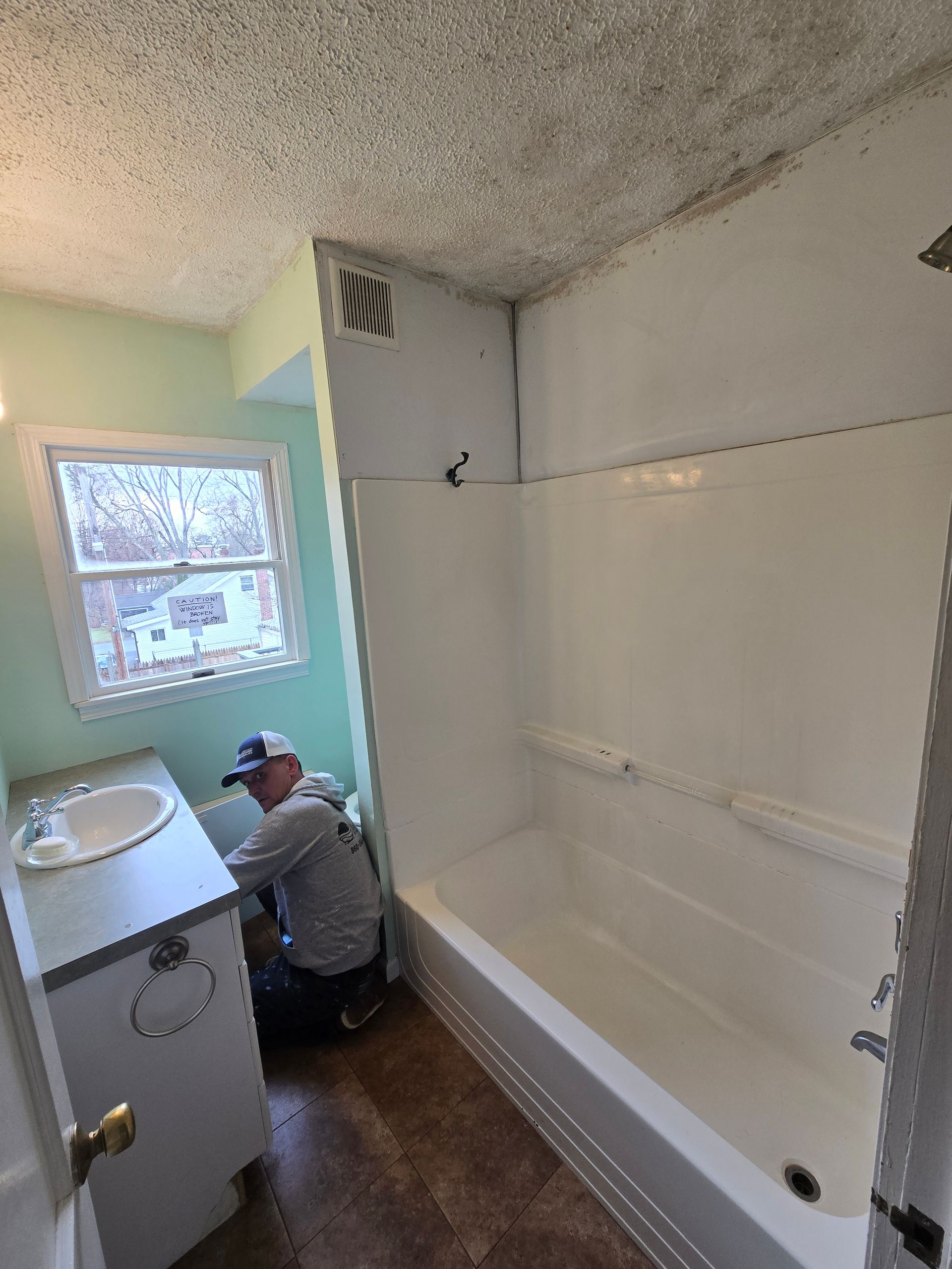 A man is working on a bathtub in a bathroom.