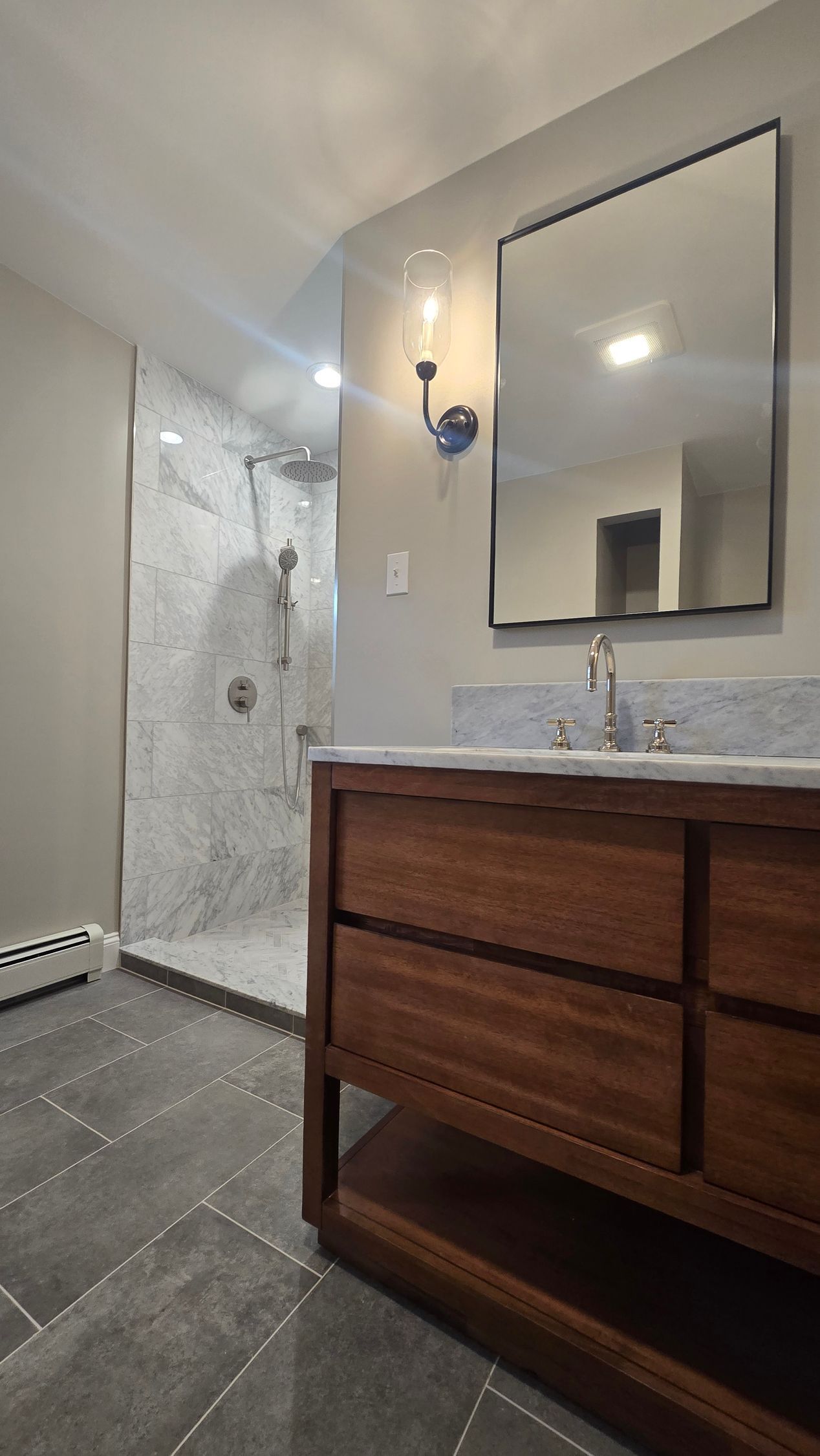 A bathroom with a sink , mirror and walk in shower.