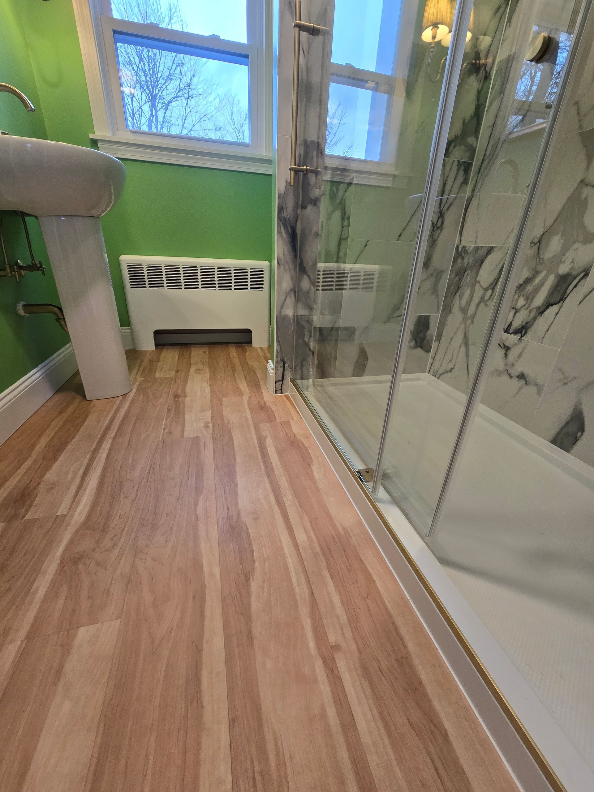 A bathroom with a walk in shower and a sink