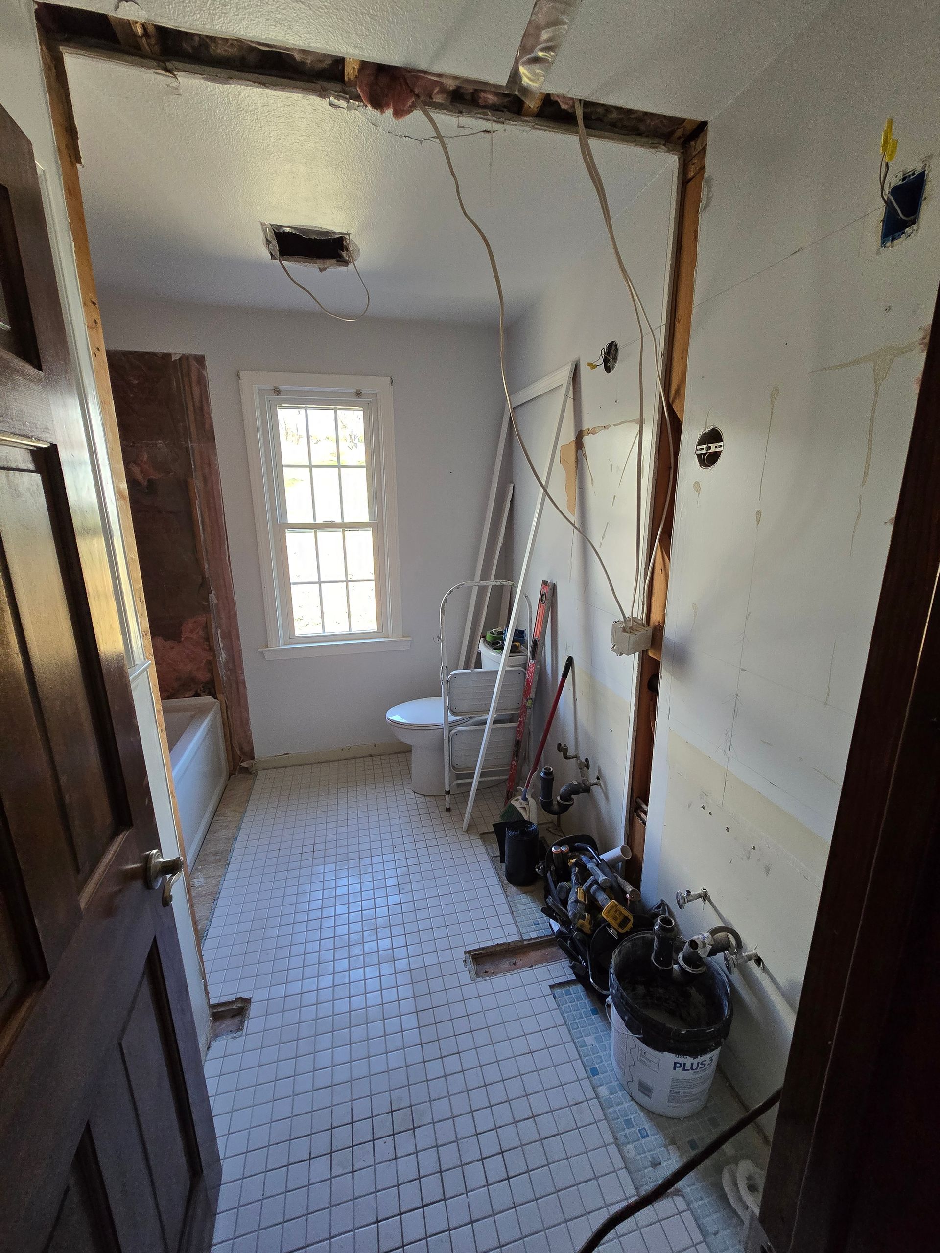 A bathroom with a toilet , bathtub and window being remodeled.