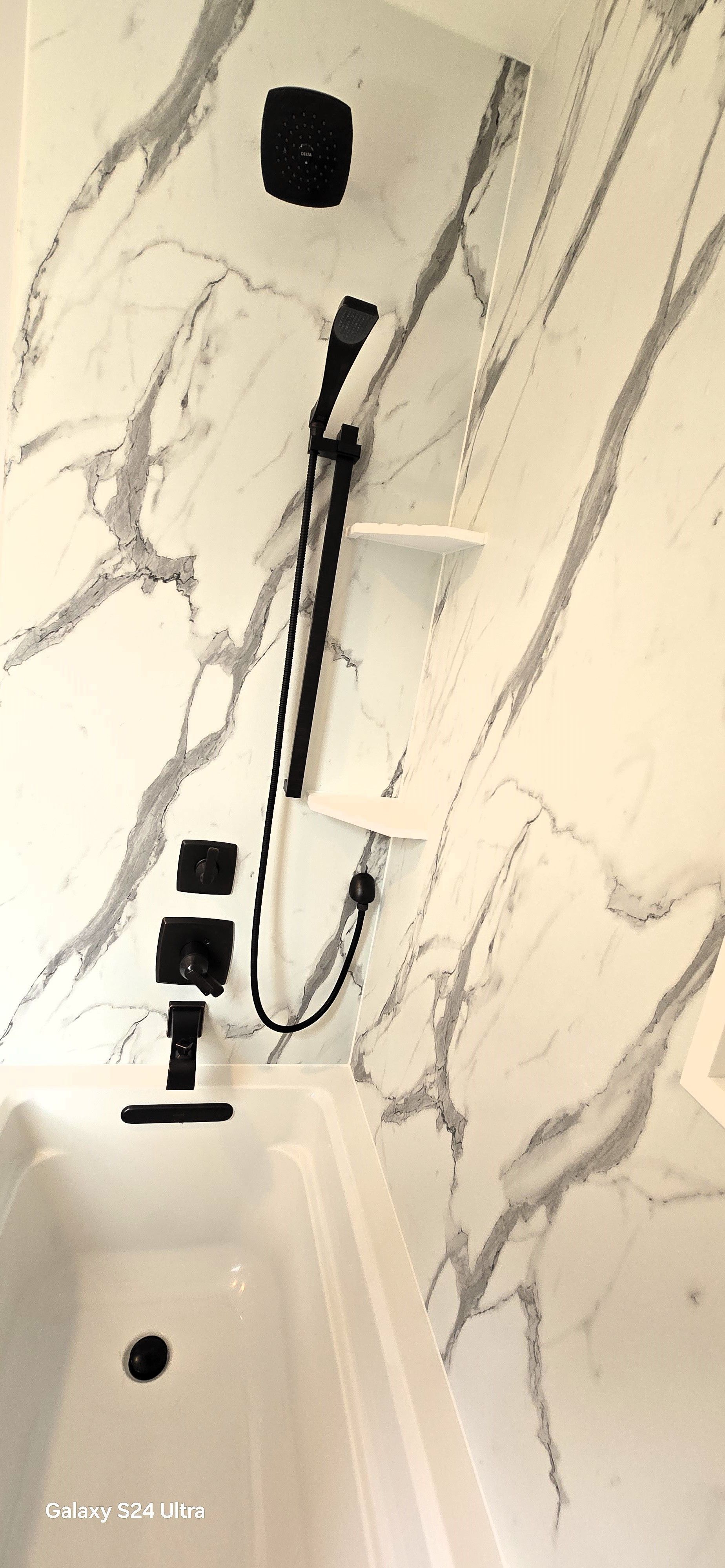 A shower with a built in shelf and a shower head