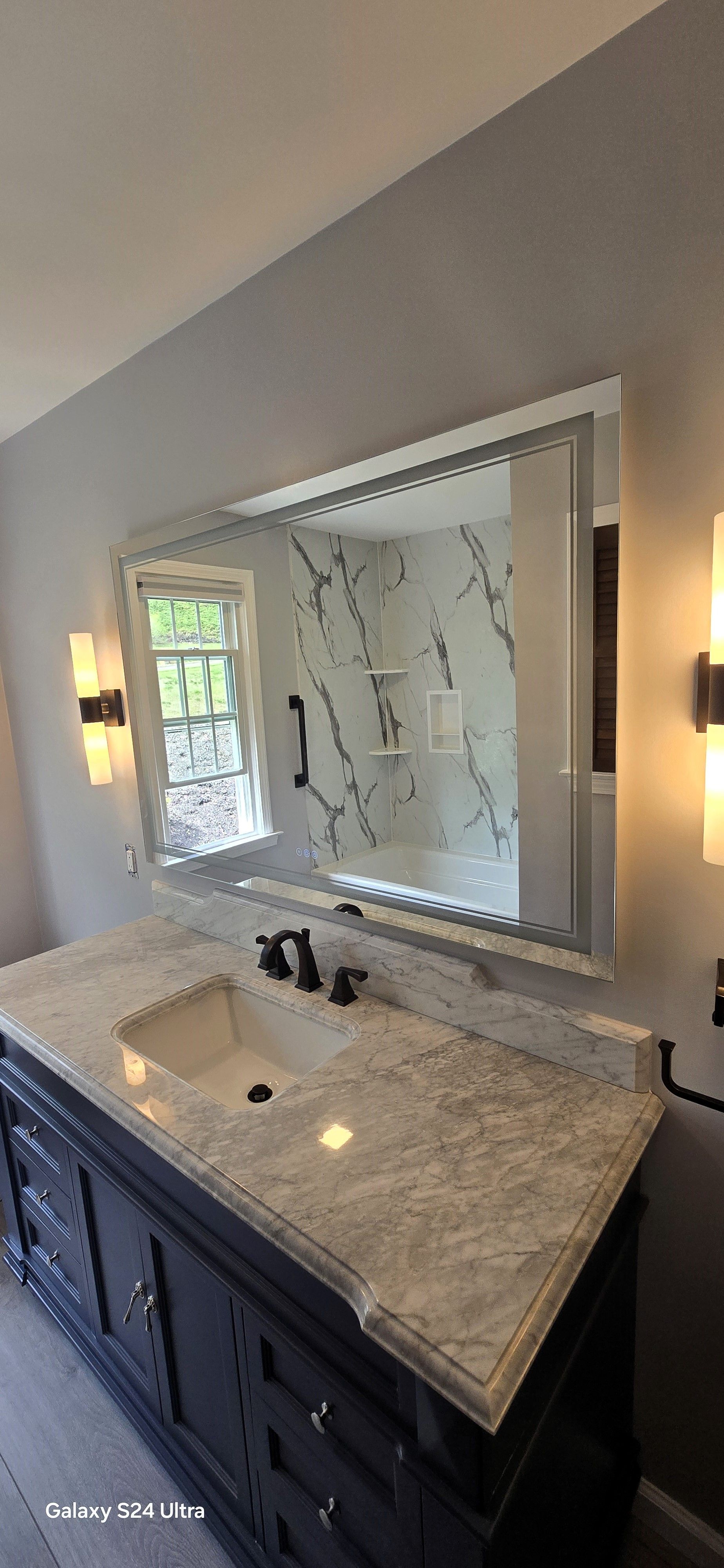 A bathroom with a sink and a large mirror.