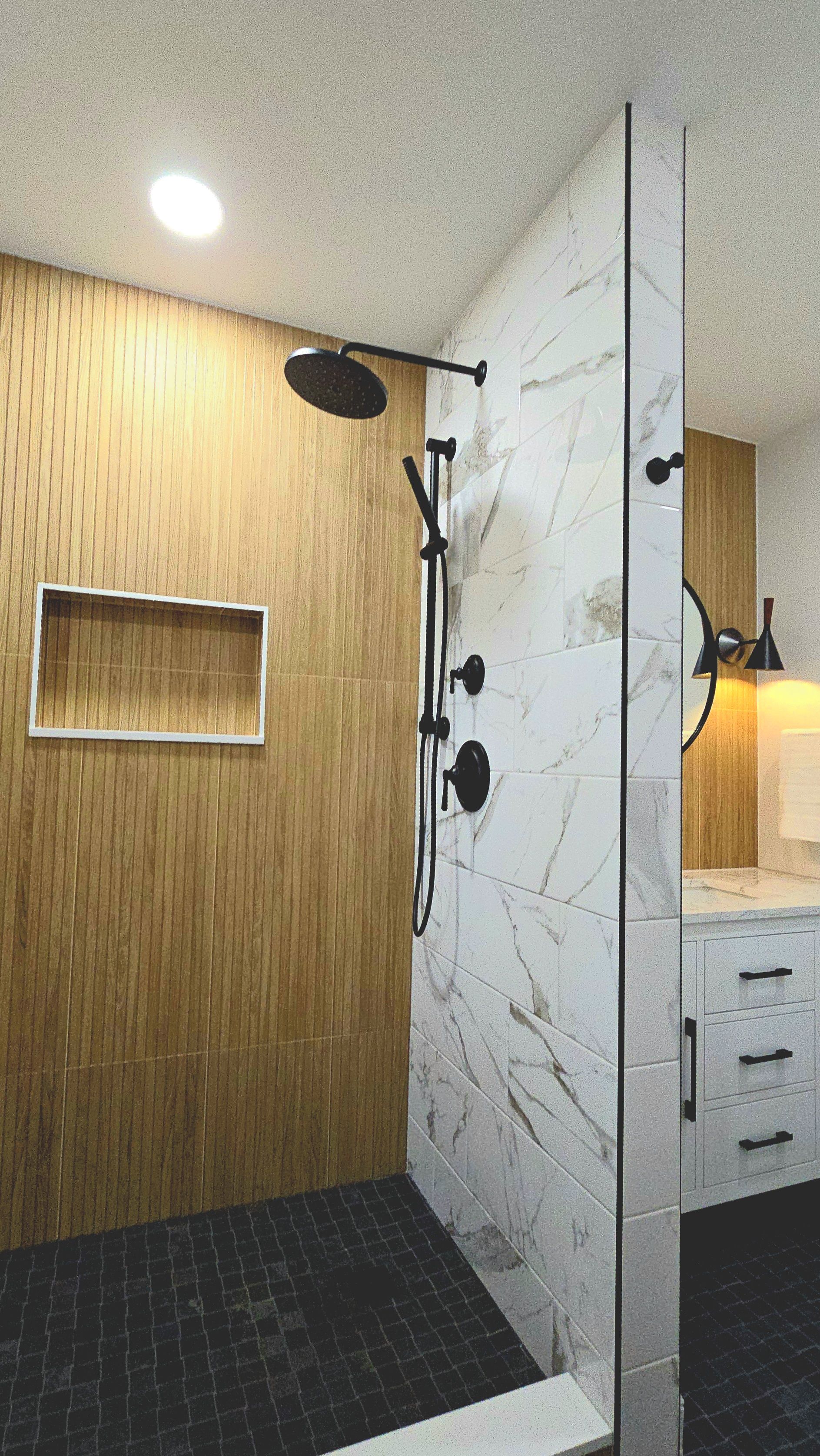 A bathroom with a walk in shower with a wooden wall and marble tiles.