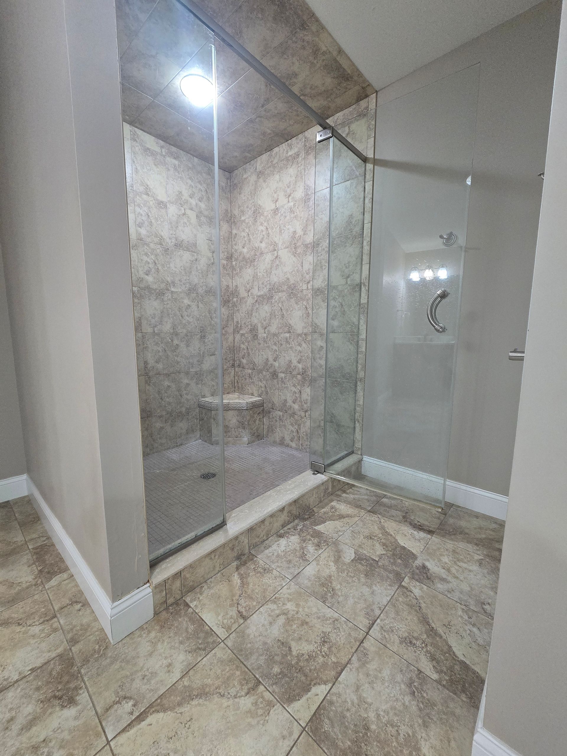 A bathroom with a walk in shower with a glass door.