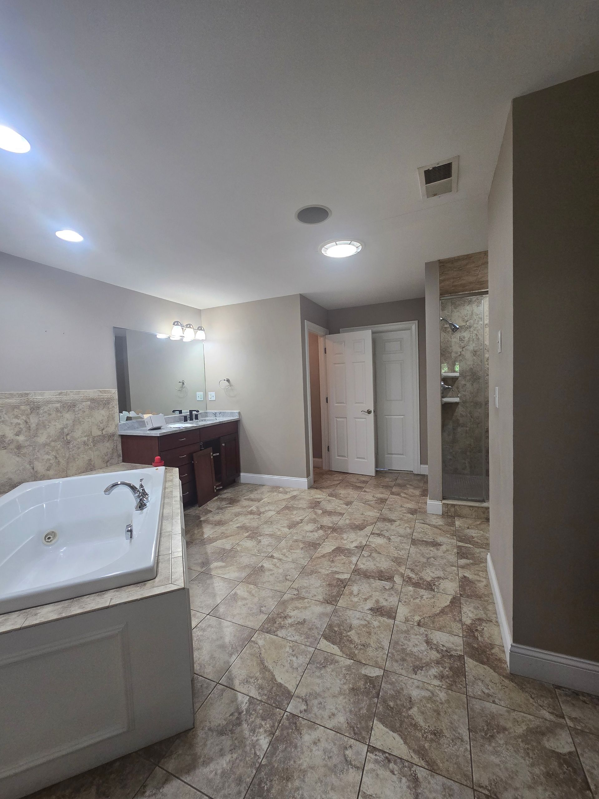A bathroom with a jacuzzi tub , sink and mirror.