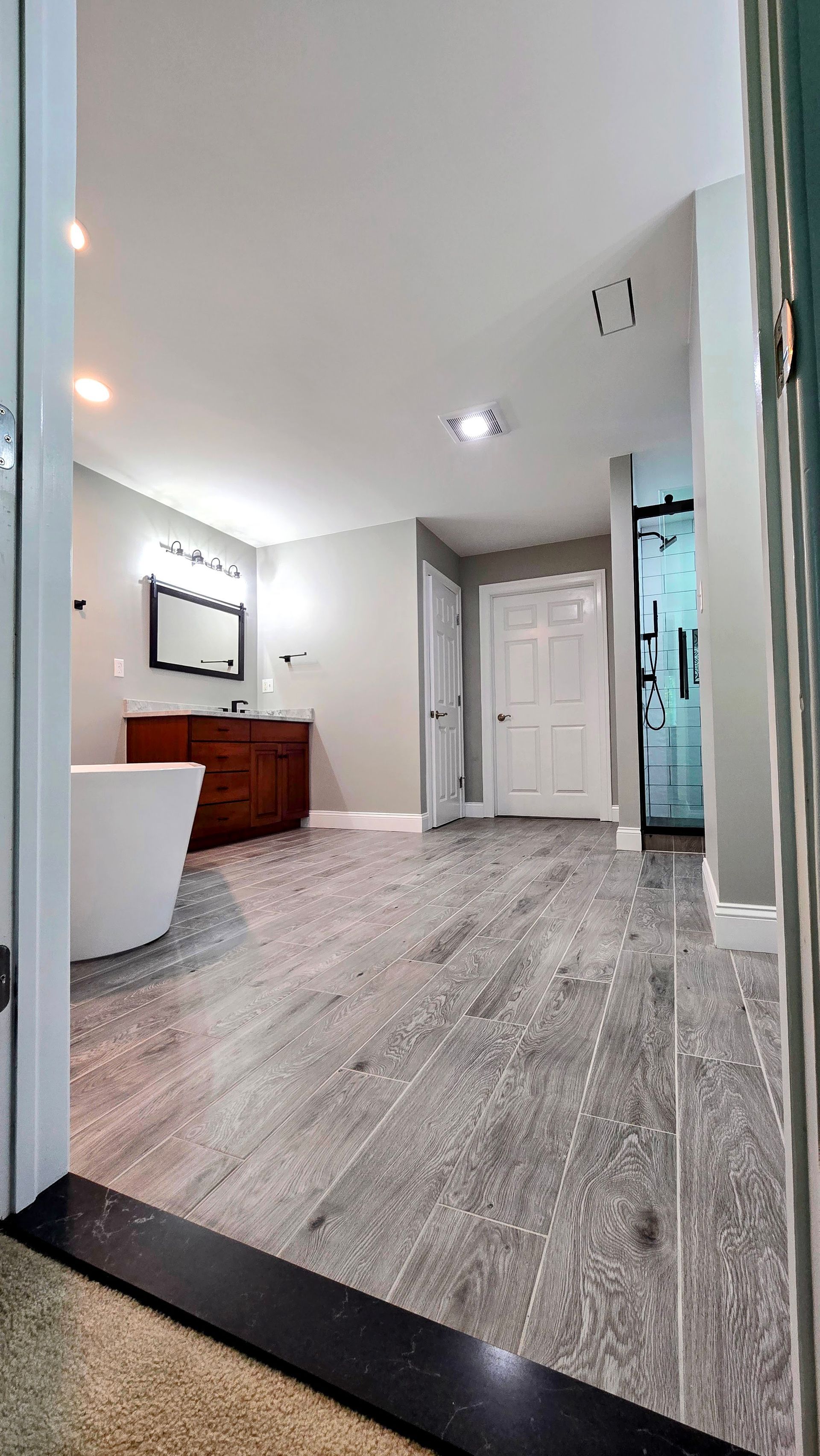 A bathroom remodel in Southington, CT with a tub , sink , mirror and door.