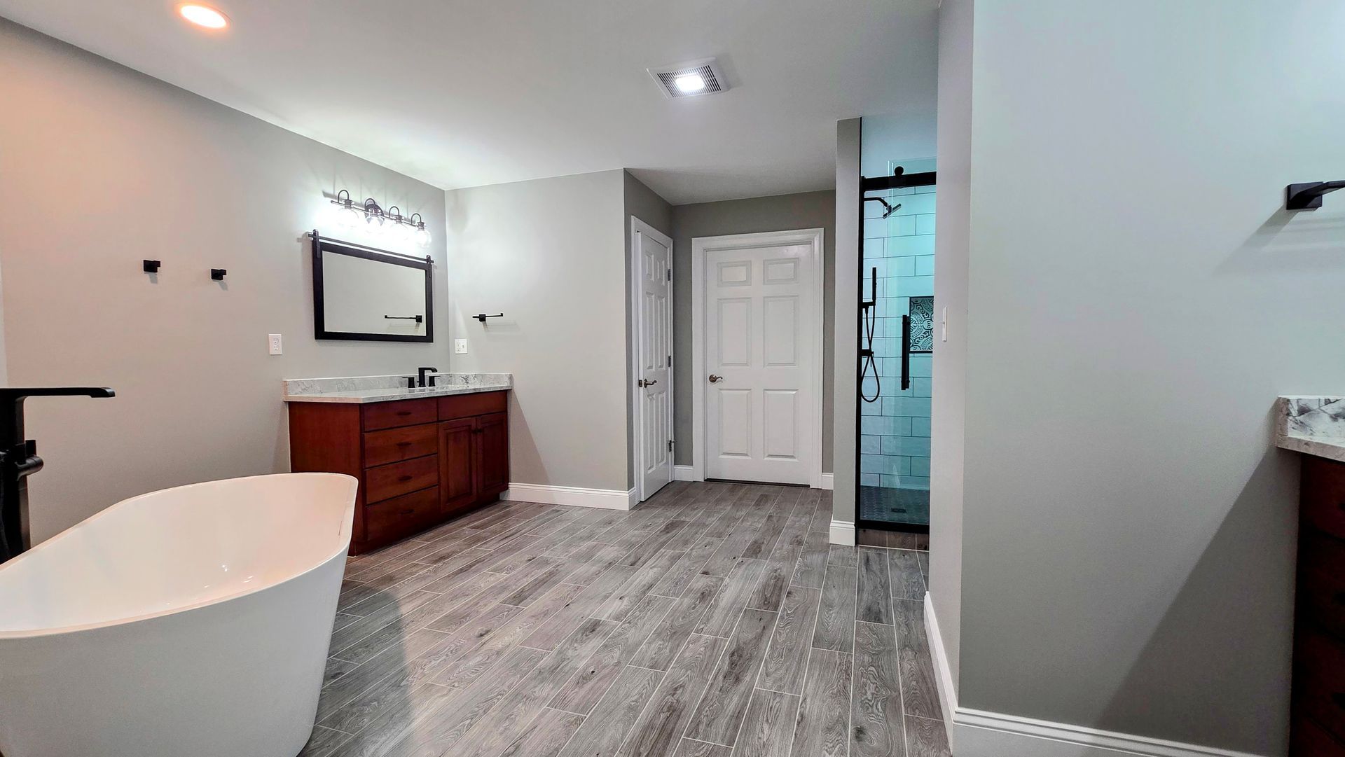 A bathroom with a bathtub , sink , mirror and walk in shower.