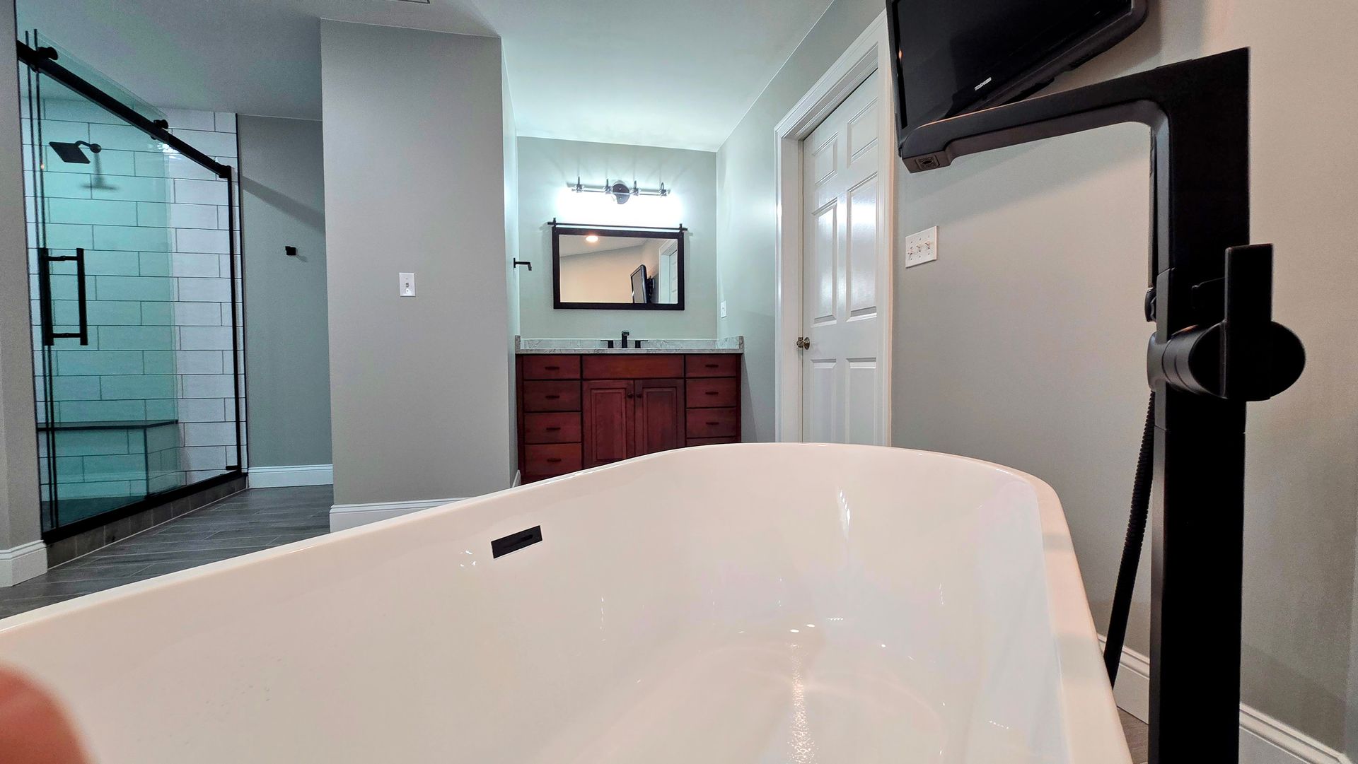 A bathroom remodel in Southington, CT with a bathtub , sink , mirror and television.