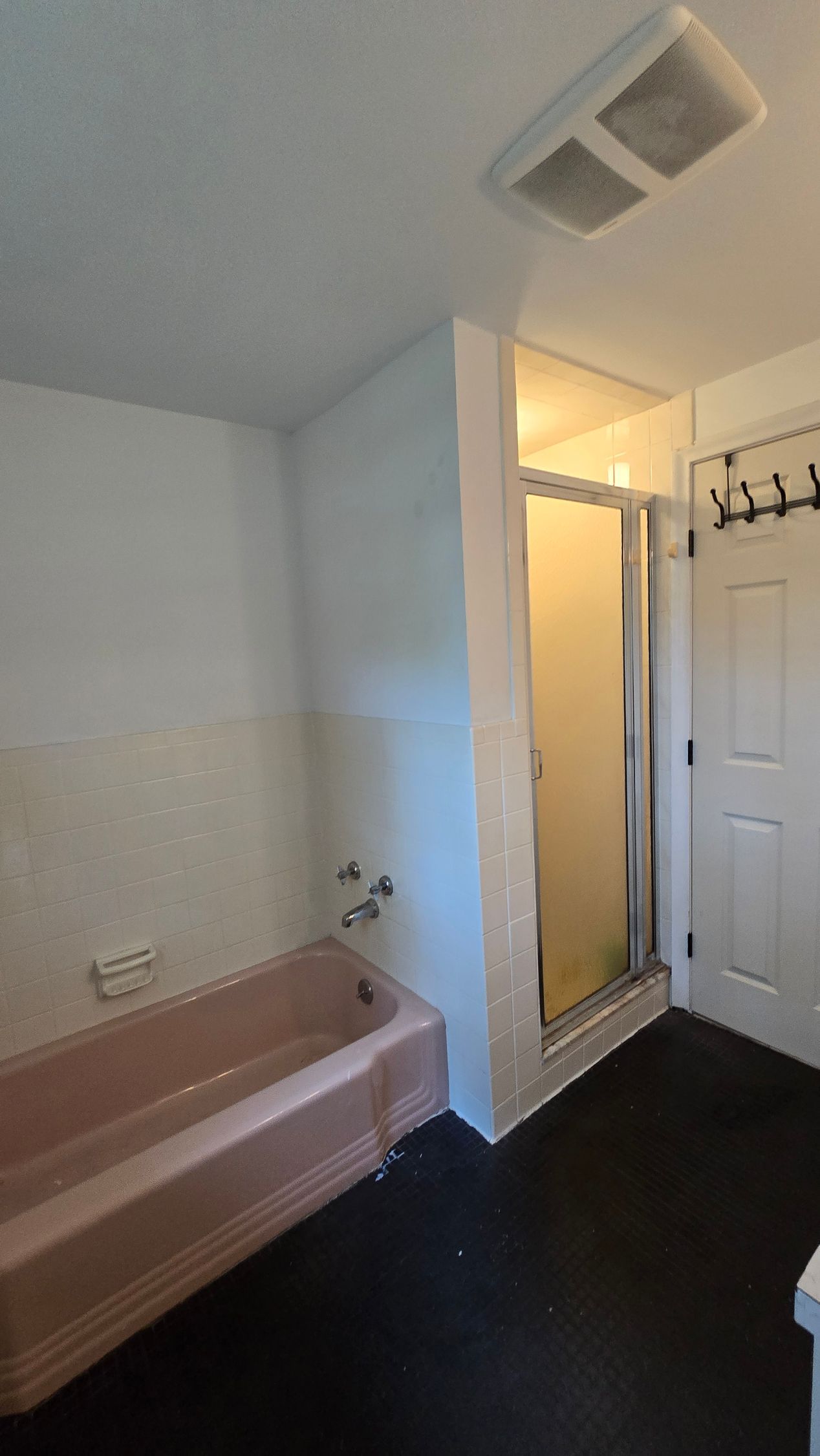 A bathroom with a tub , toilet , sink and mirror.