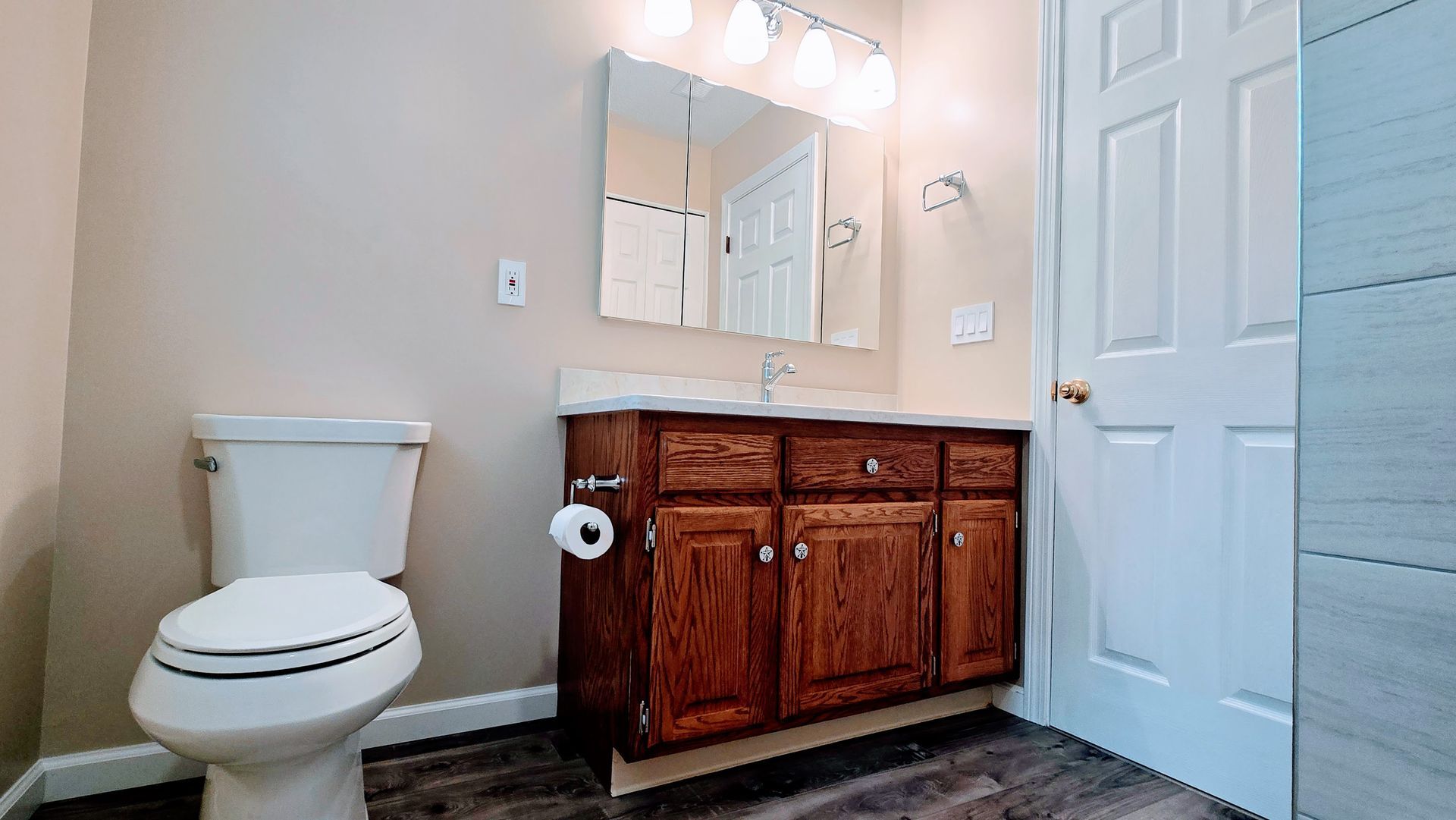 A bathroom with a toilet , sink and mirror.