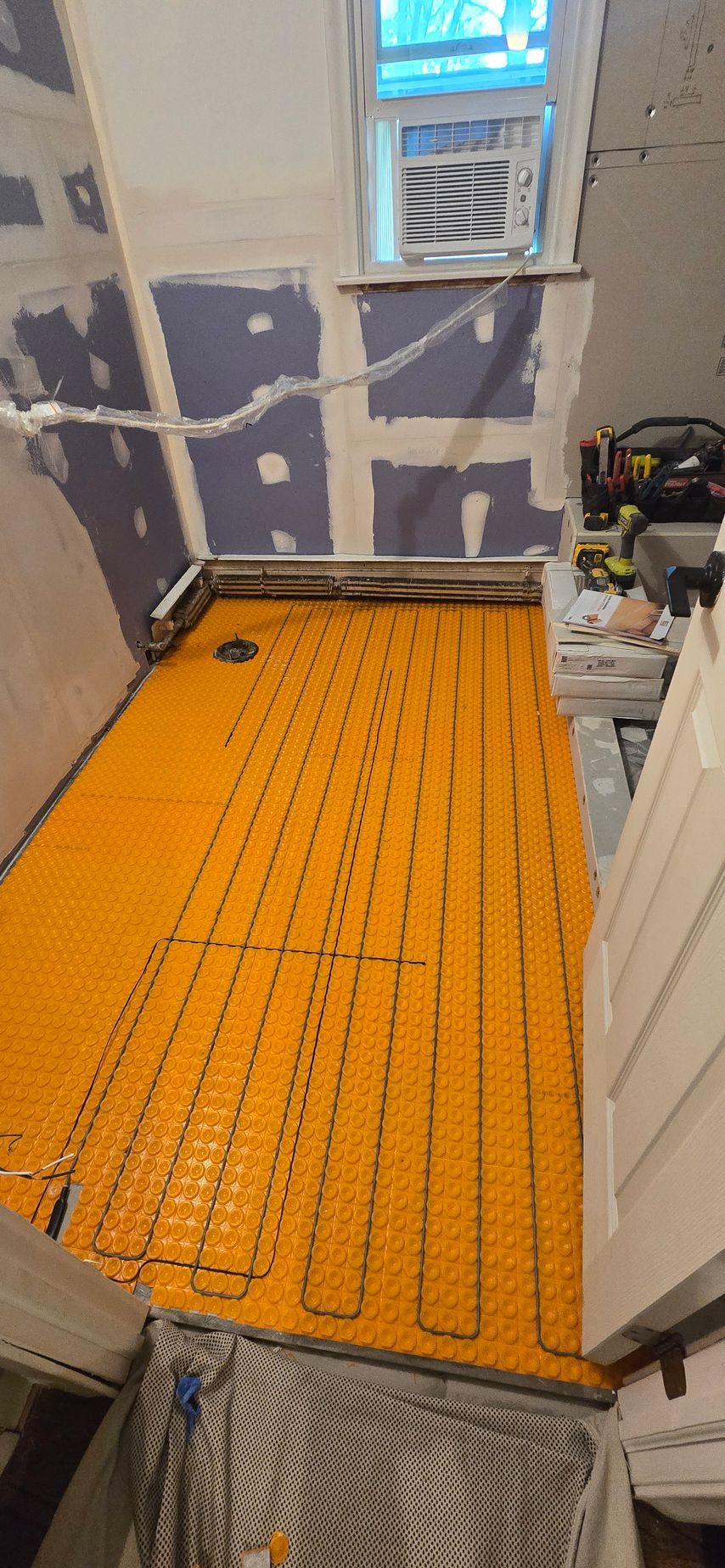 A yellow underfloor heating system is being installed in a bathroom.