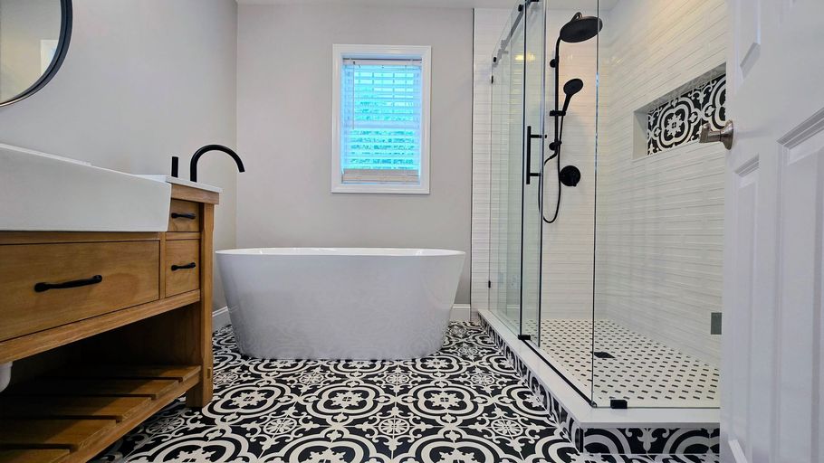 Modern Bathroom remodel in Prospect, CT with black and white patterned tile, a white tub, shower, and light wood vanity.