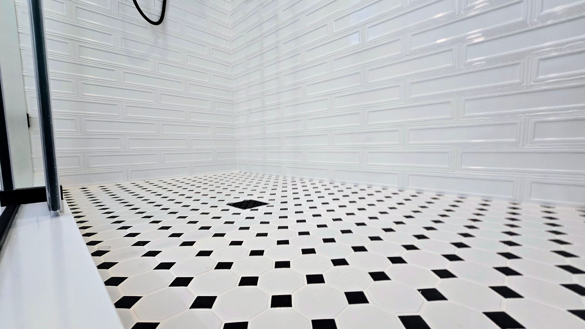 A black mosaic tiles on the shower floor and white photo of a tiled floor with a honeycomb pattern.