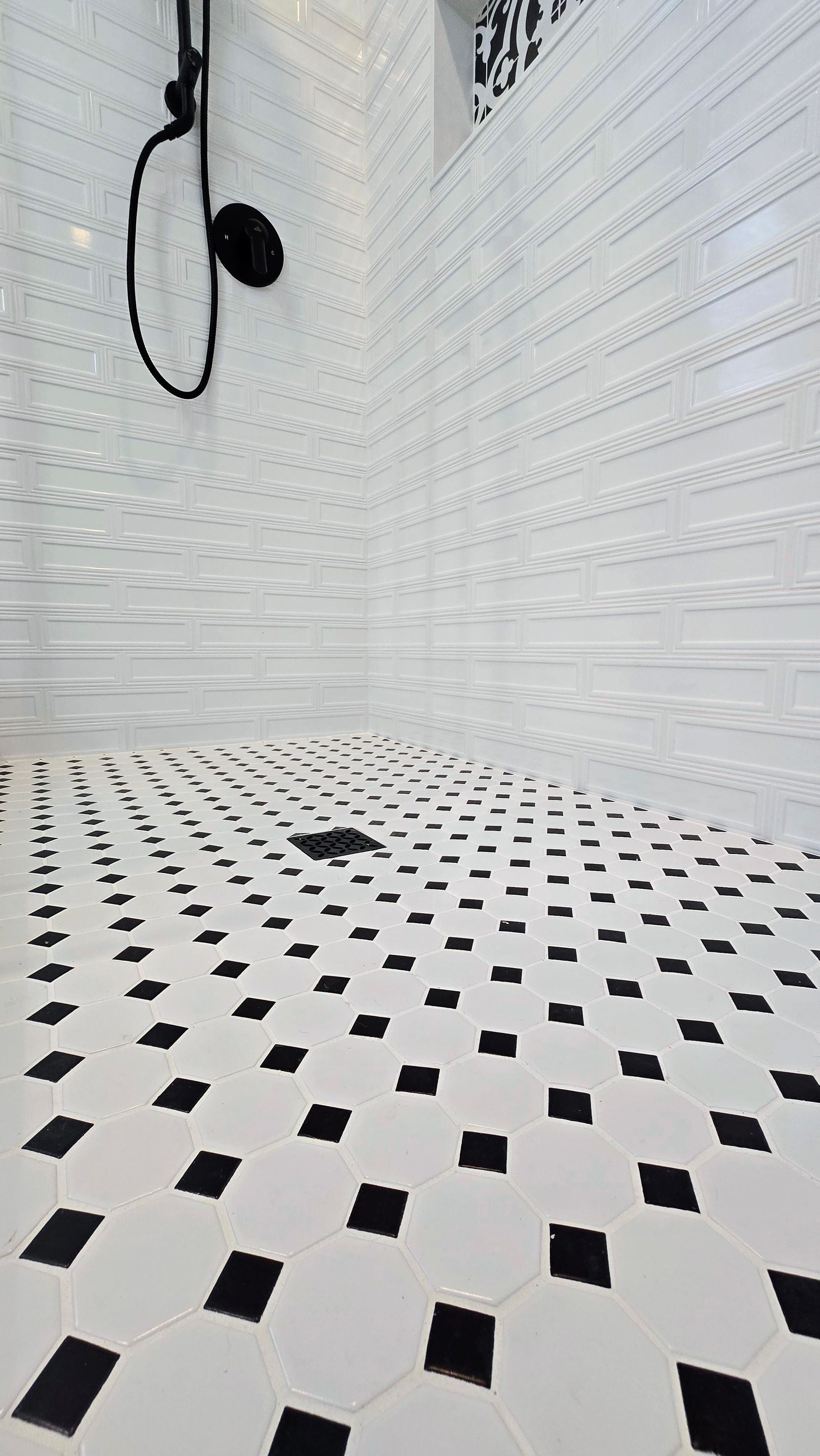 Black and white tiled shower with black showerhead.