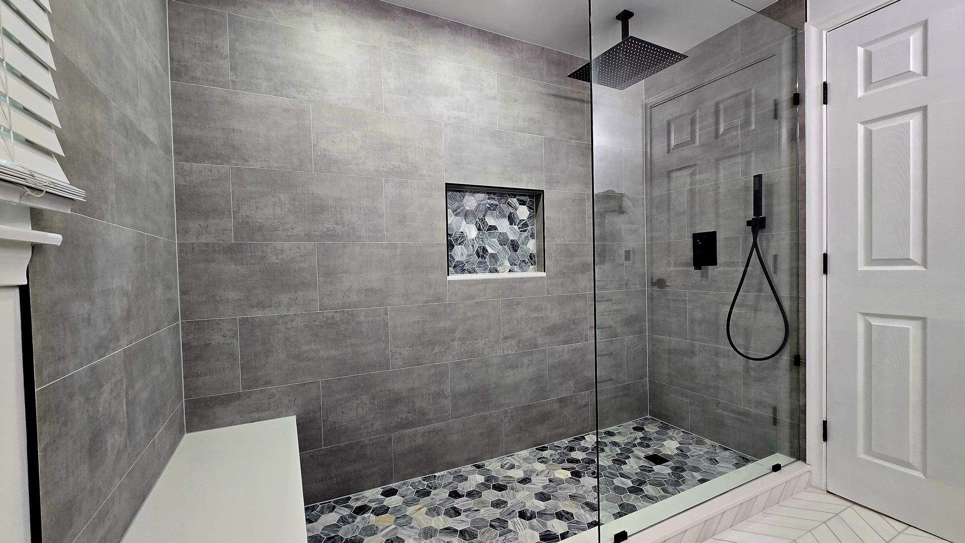 A bathroom with a walk in shower and a bench.