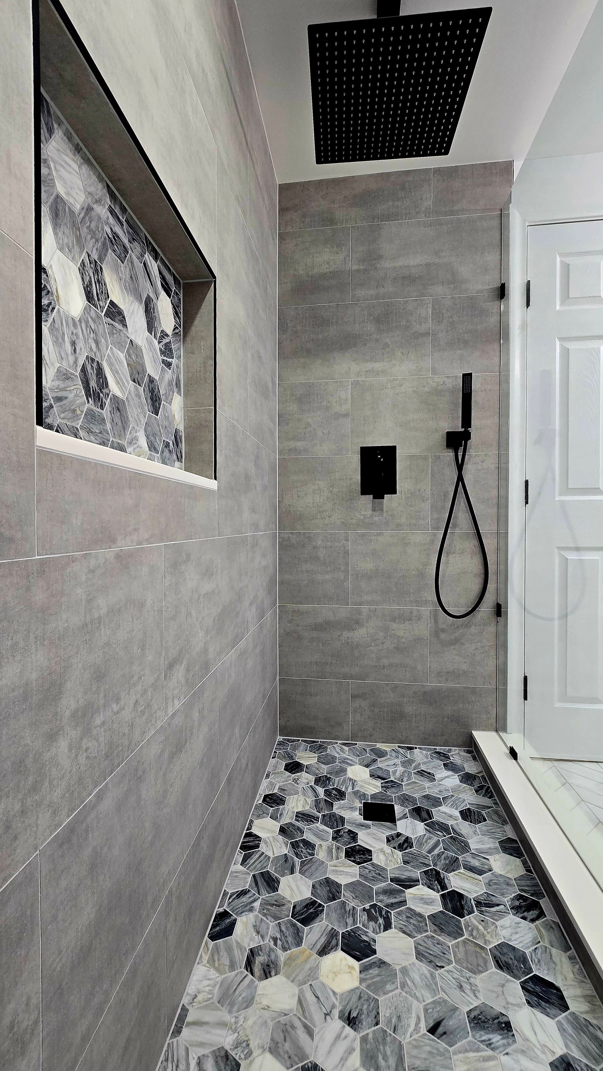 A bathroom with a walk in shower and a black shower head.