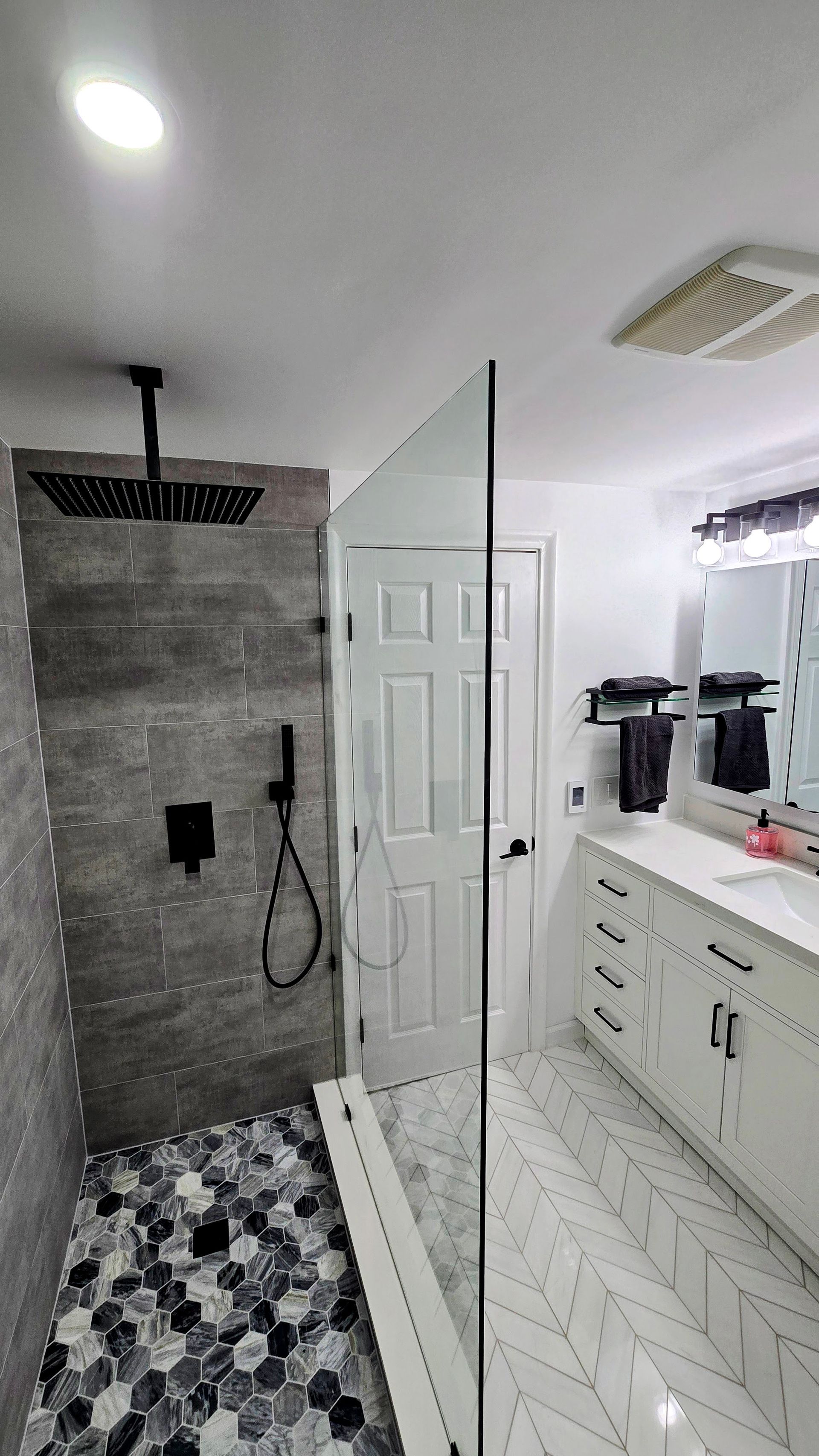 A bathroom with a walk in shower and a sink.