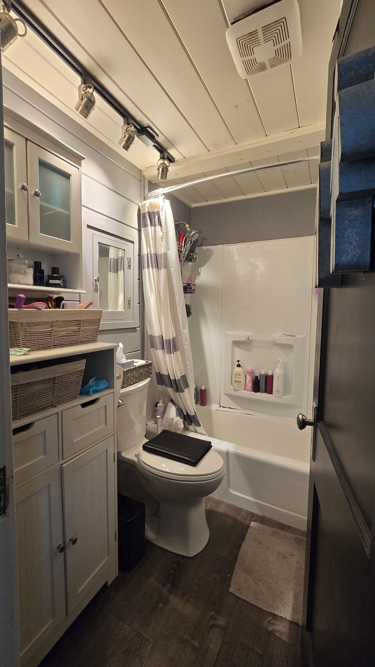 Small West Hartford bathroom with toilet, shower, sink, white walls, wood ceiling.