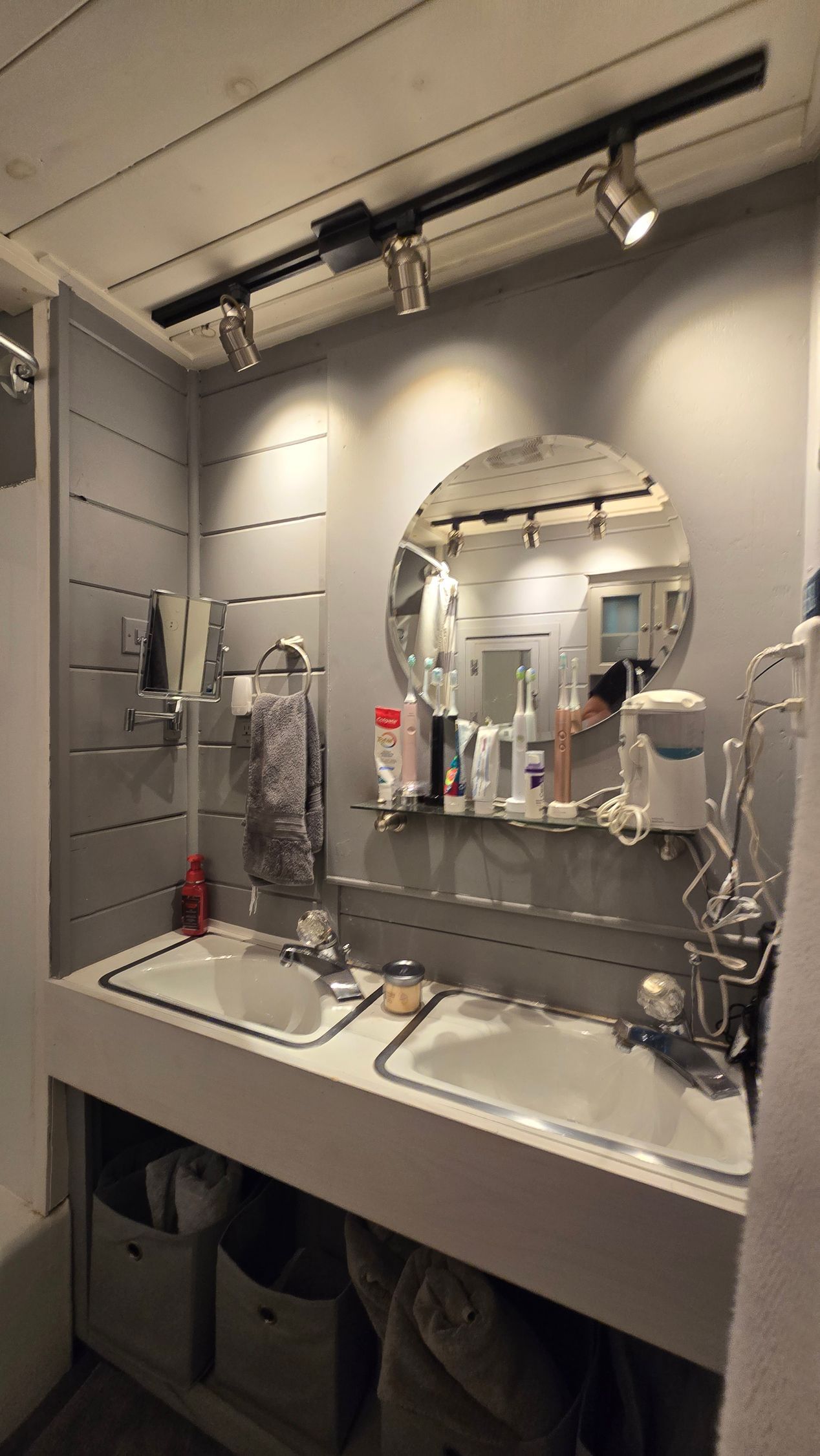 West Hartford Bathroom with two sinks, a round mirror, shelving, and track lighting.