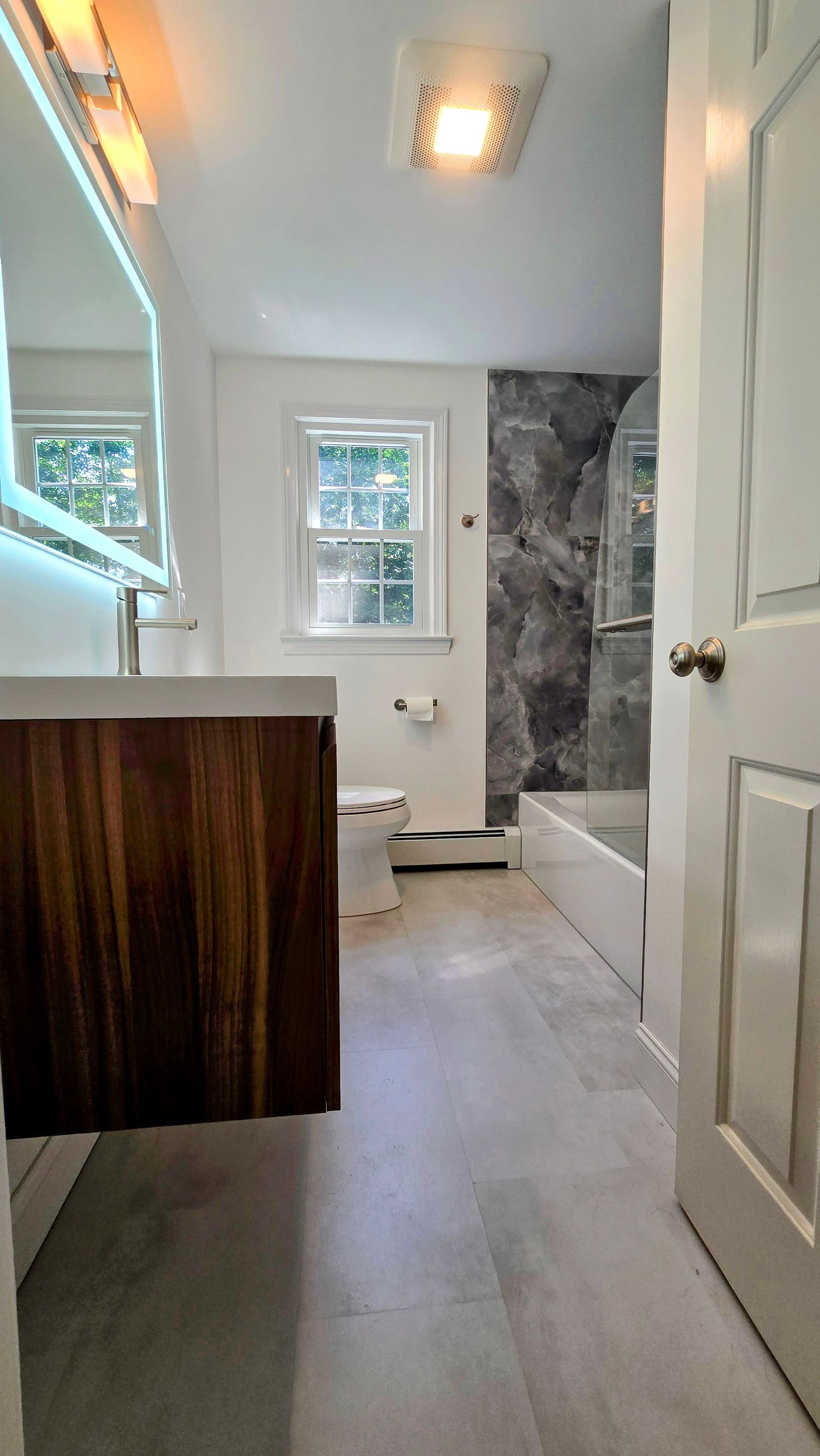 A walk in shower with a bench and a shower head.