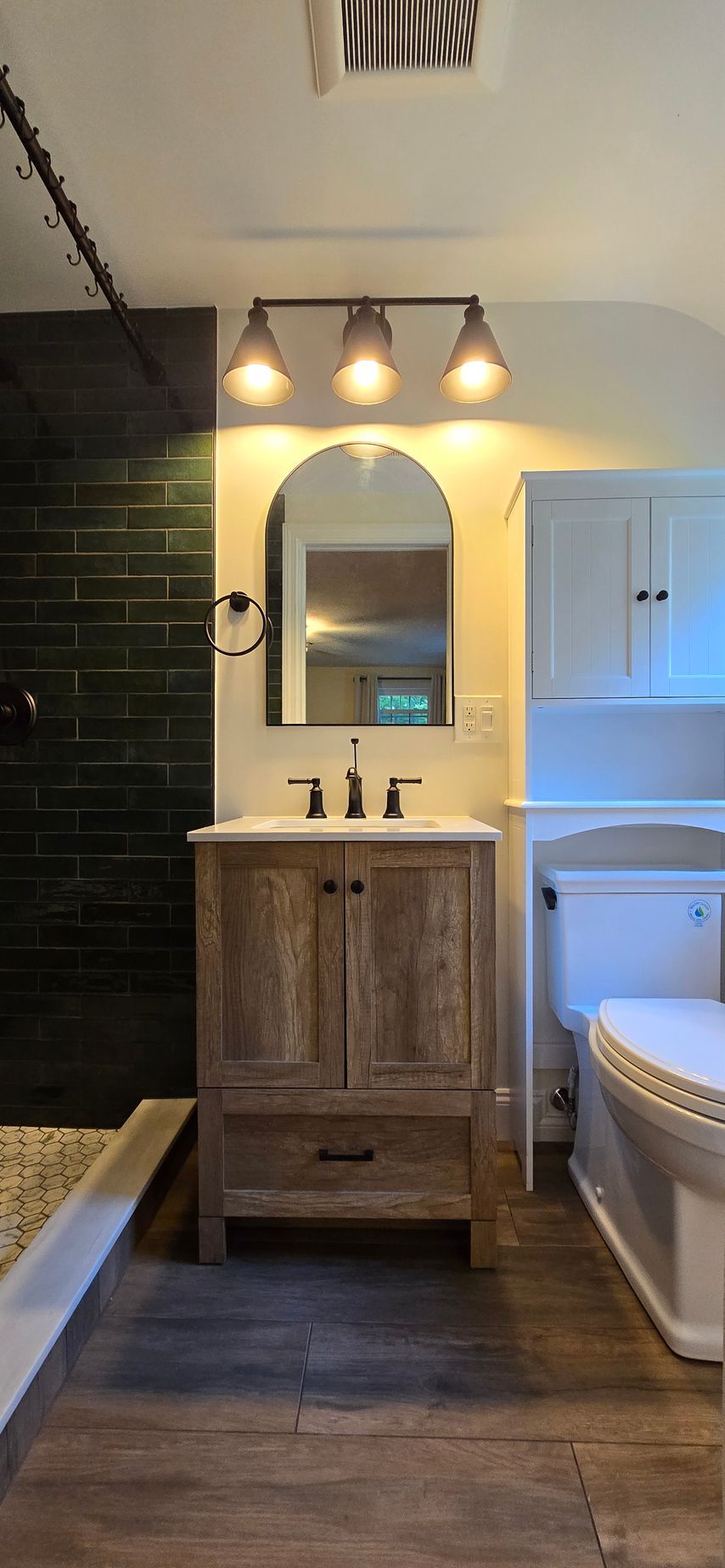 Modern bathroom with a wooden vanity, large mirror with LED lights, and a toilet in Simsbury CT.