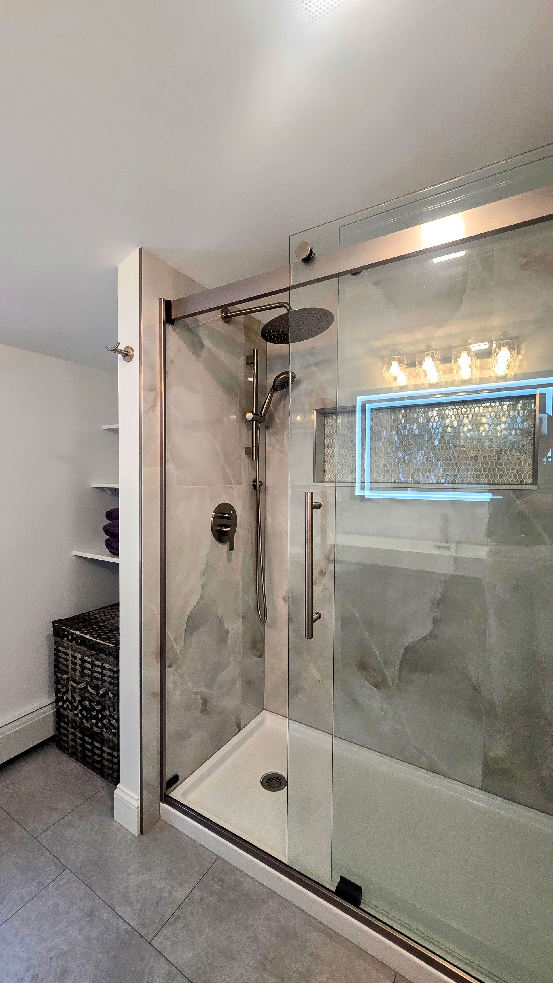 Modern bathroom with glass shower, marble-like tile, and overhead showerhead.