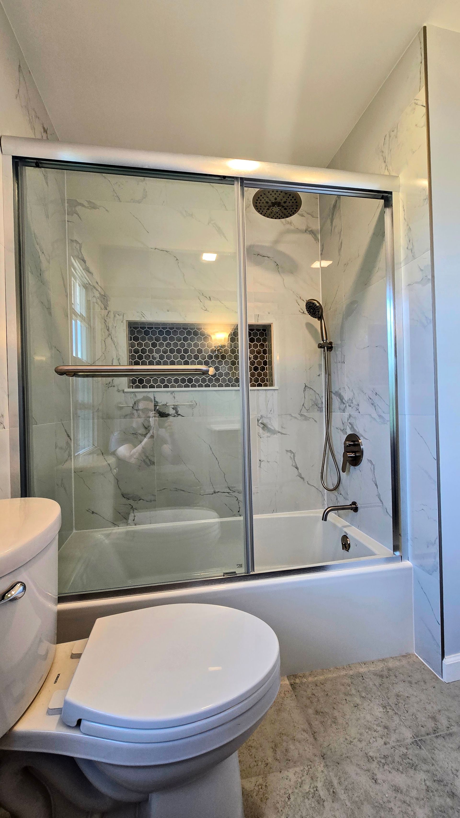 Bristol Bathroom with white bathtub, stone tile shower, black shower fixtures, recessed shelf.