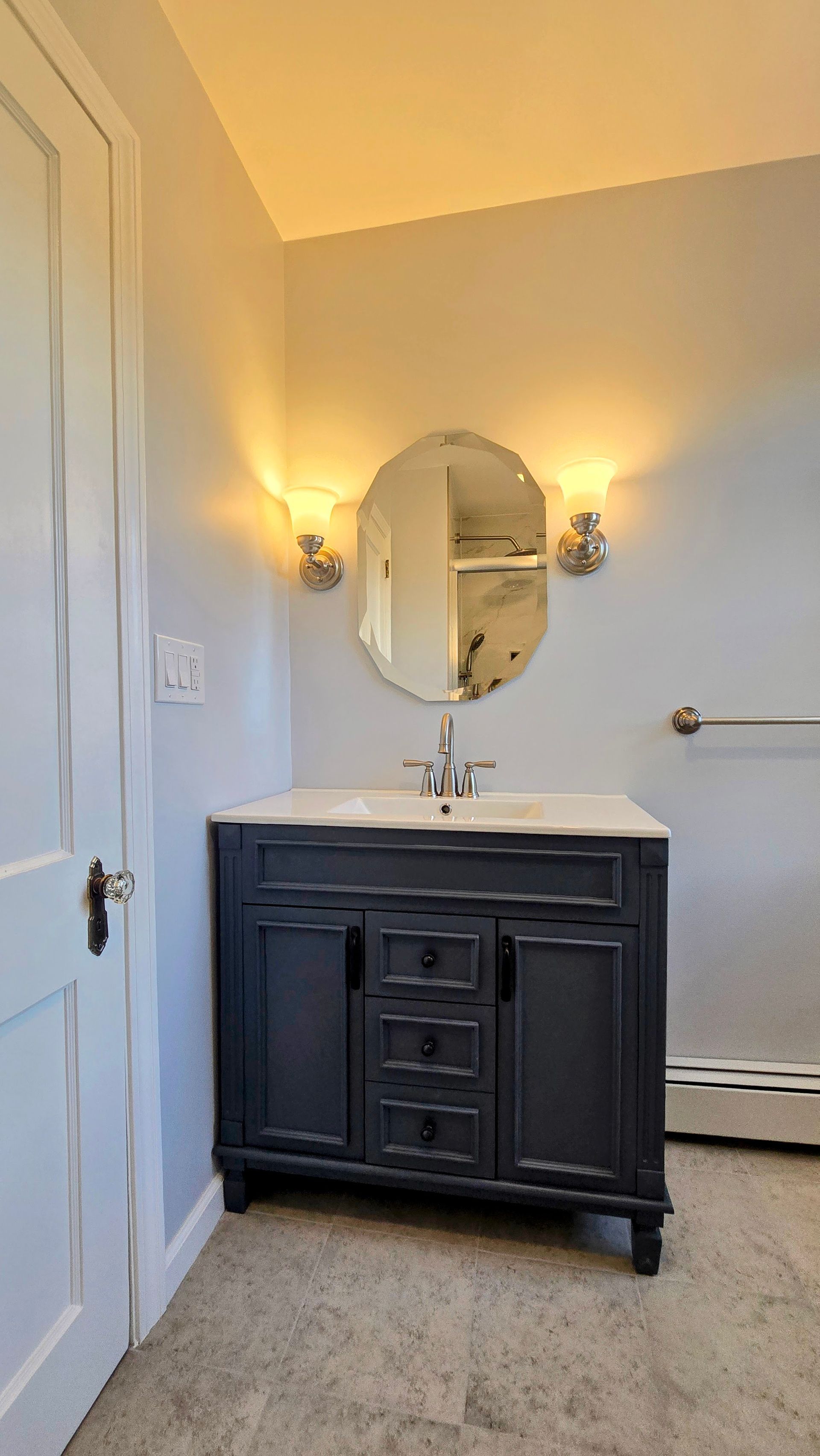 Bristol bathroom with large, illuminated mirror over a white countertop, black faucets, and a sink.