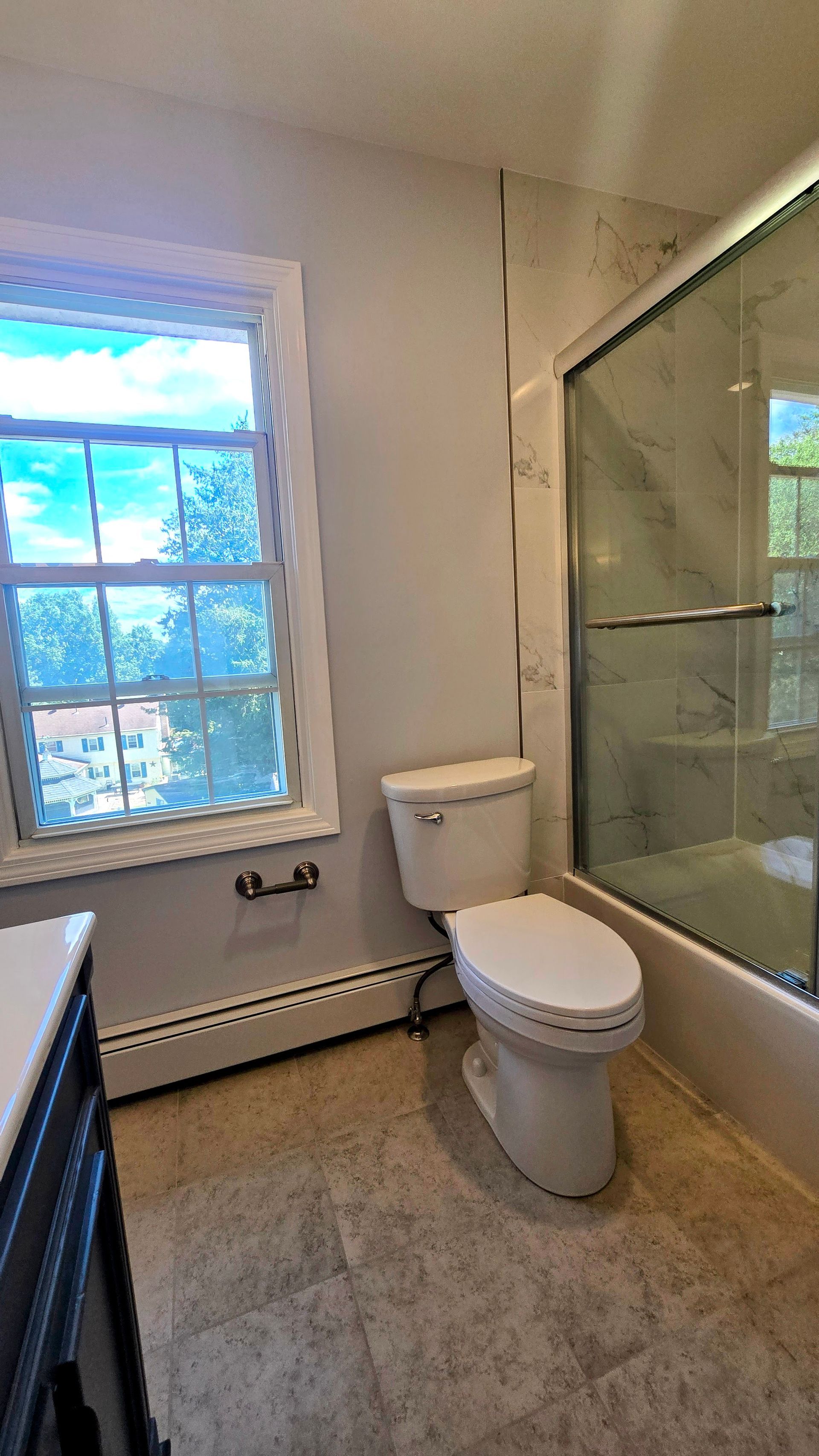 Bristol bathroom with white tub, speckled tile wall, black shower fixtures, and a recessed shelf.