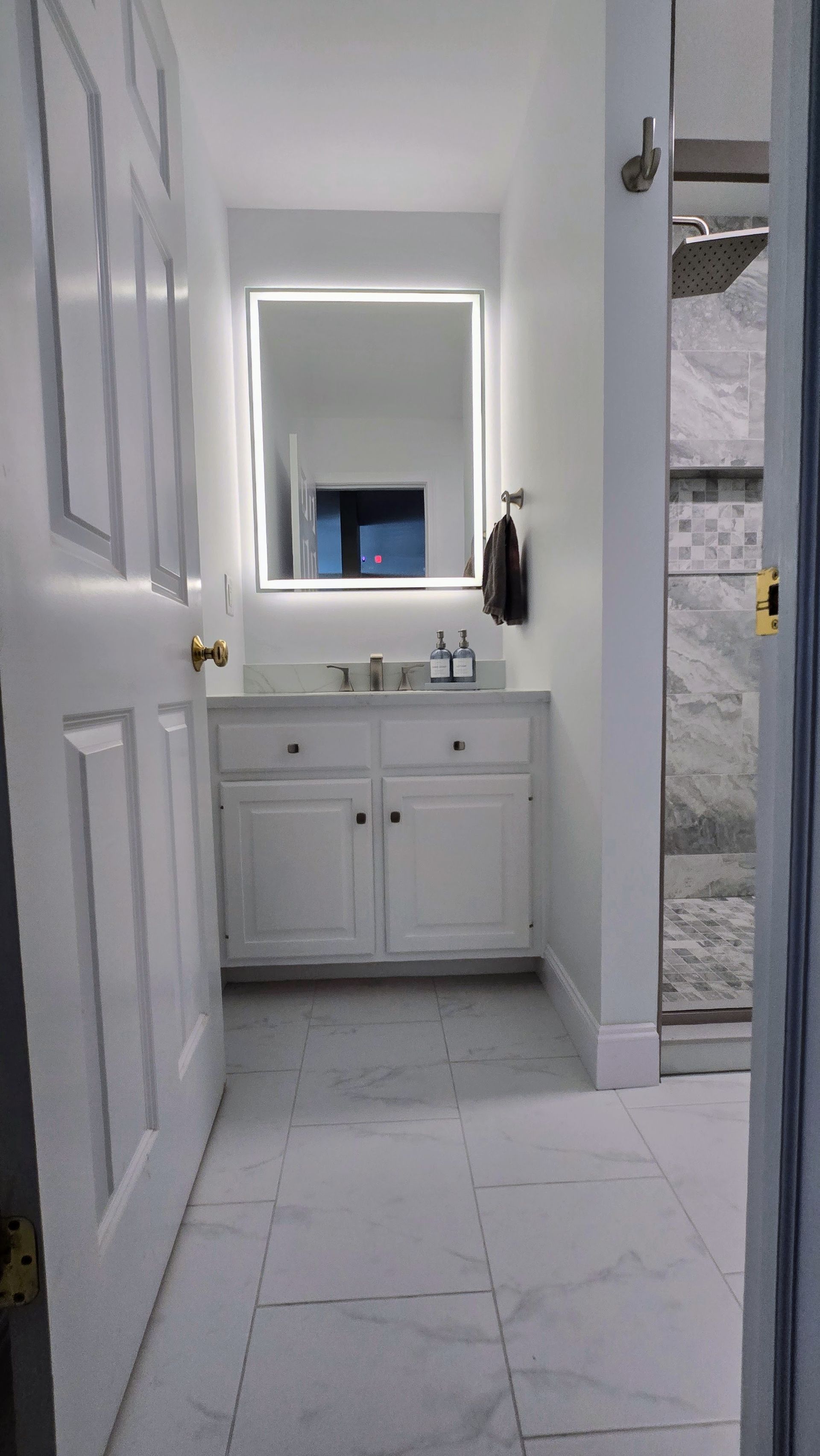 Bathroom with blue walls, dark vanity, and marble-patterned floor.  A window and a large mirror are present.