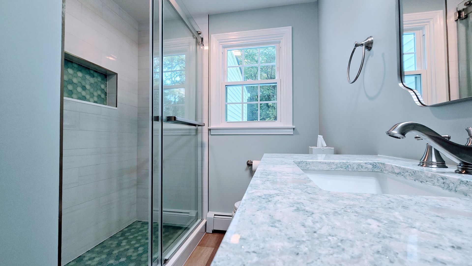 Bathroom with jacuzzi tub, vanity, toilet. Light beige walls, brown cabinets, glass shower door.