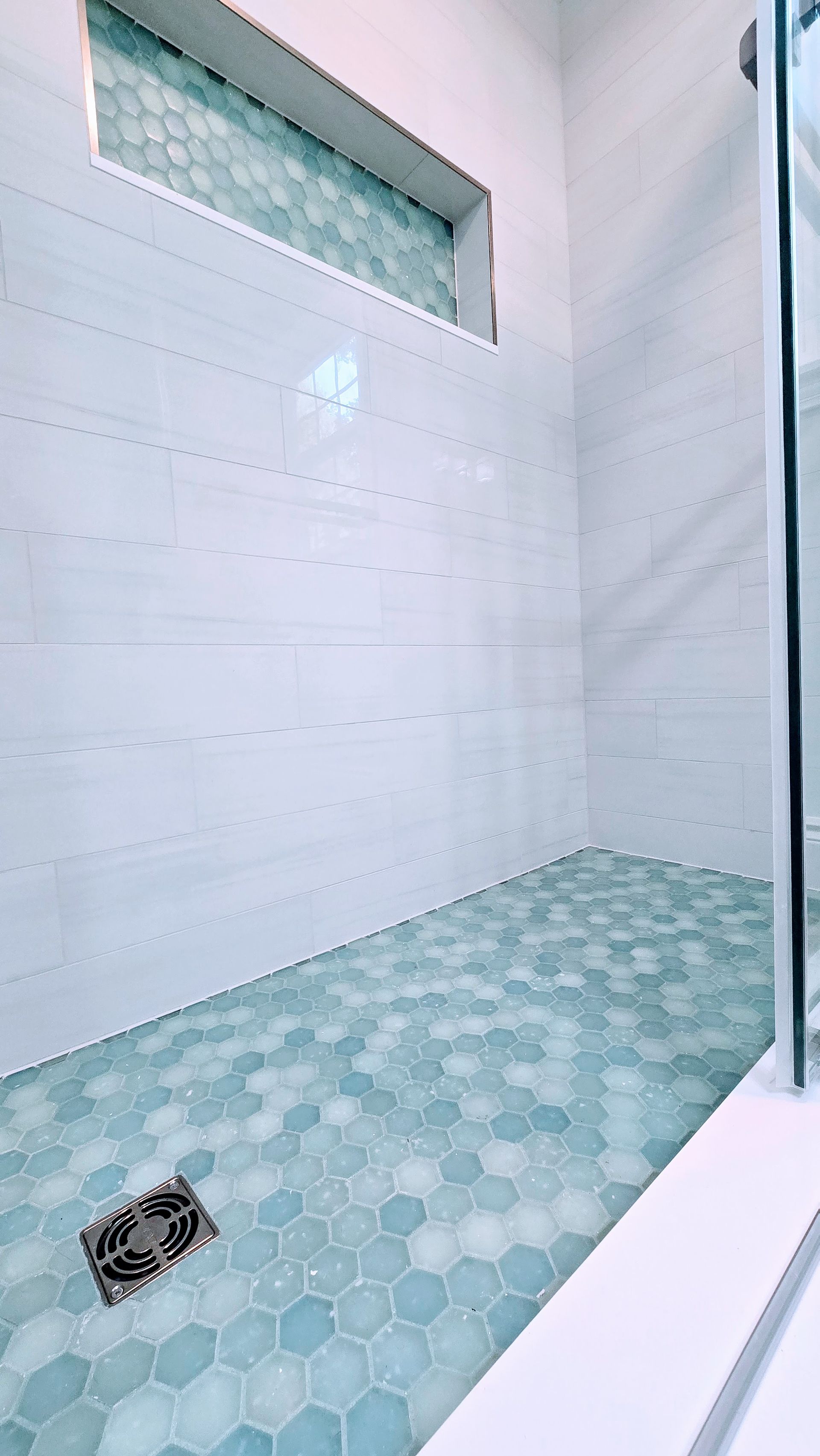 White built-in shelf with three sections in marble-tiled wall. A bar of soap rests on middle shelf.