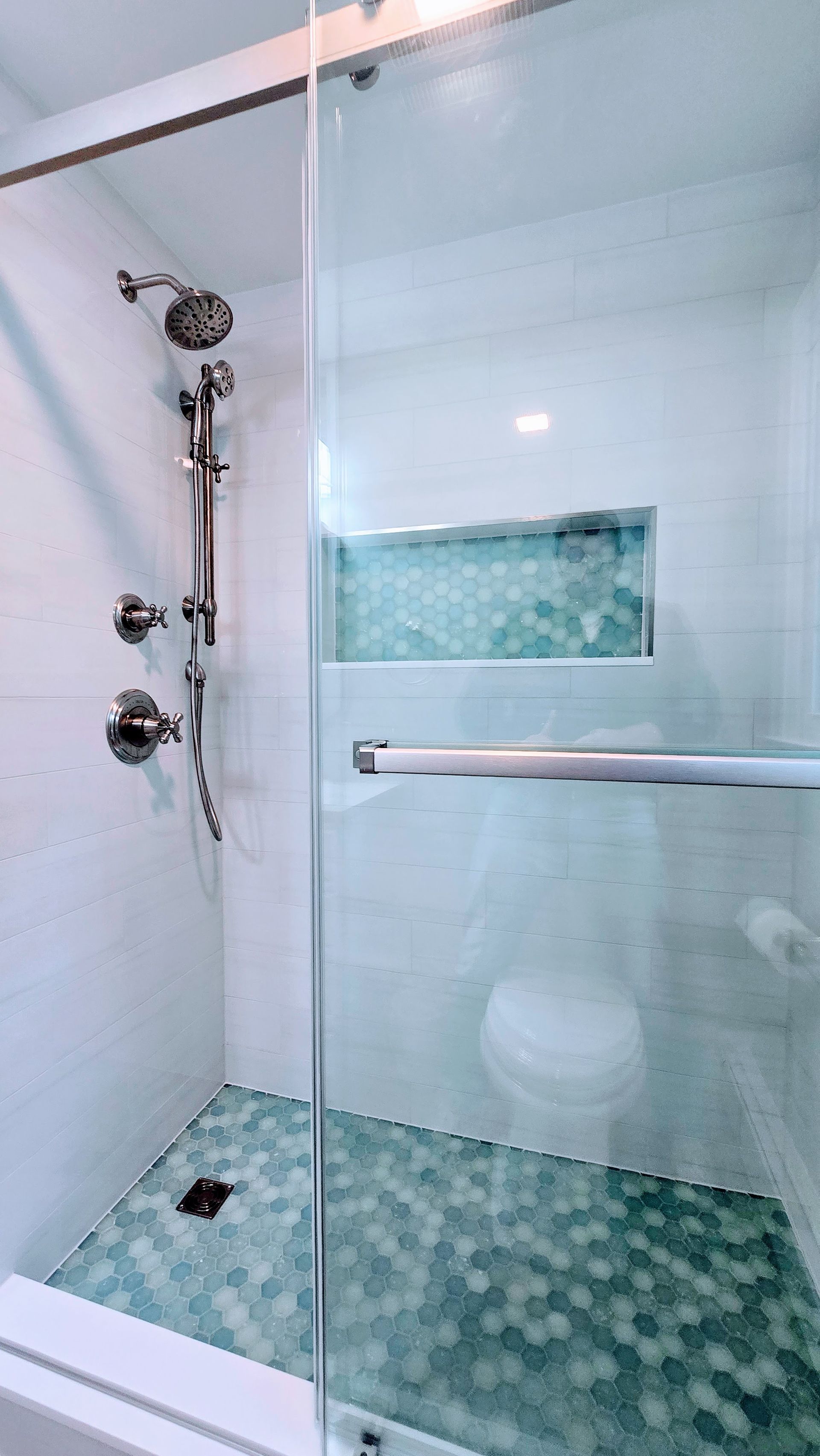 Walk - in Shower in Bristol, CT with glass doors, teal hexagon tile floor, white and teal tile walls, chrome fixtures.