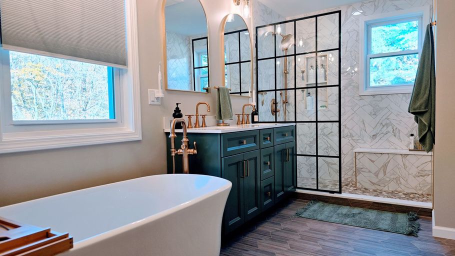 Modern bathroom  in Simsbury, CT with a freestanding tub, dark green vanity, and black-framed shower.