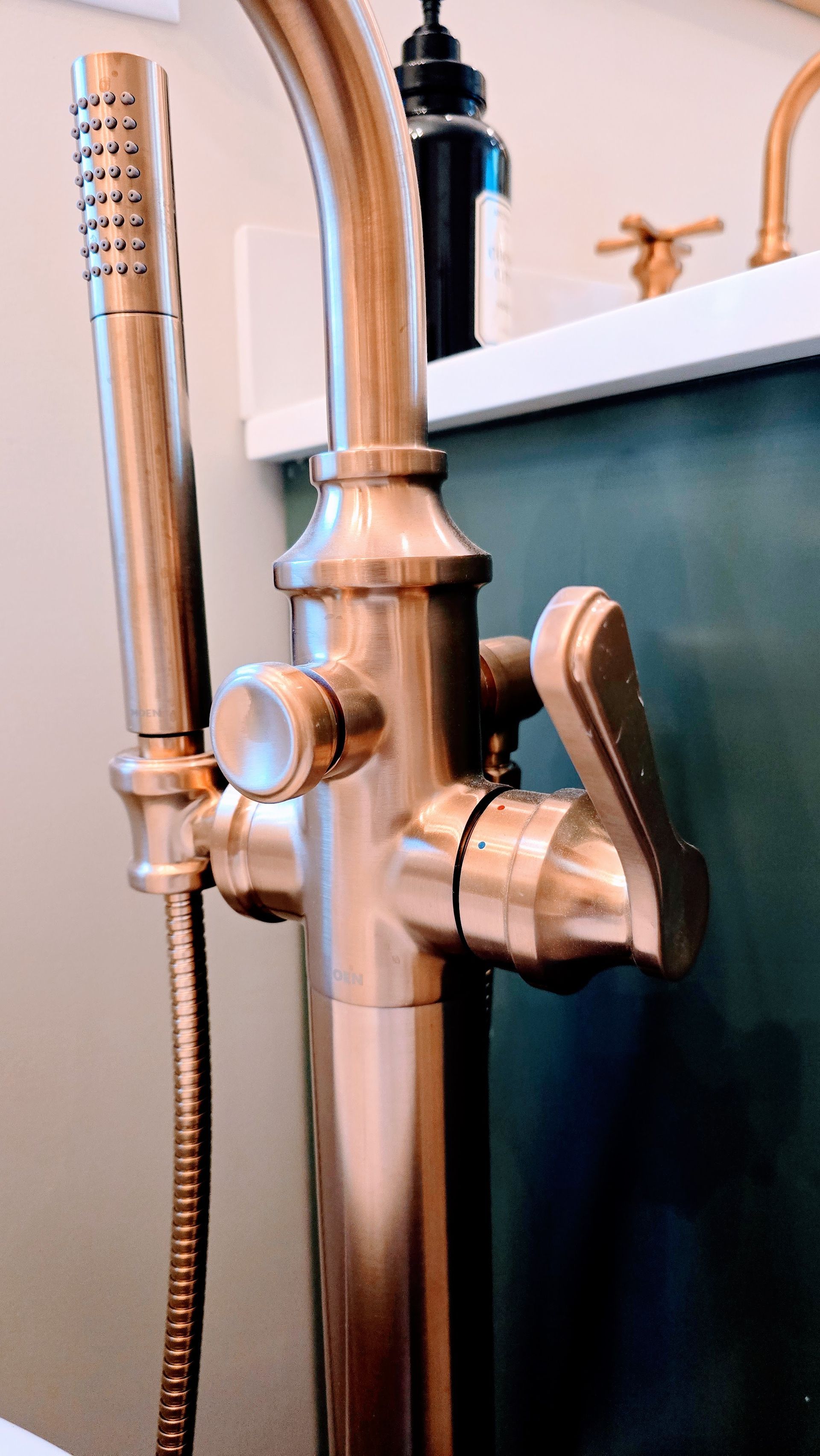 Copper-toned freestanding bathtub in Wolcott, CT faucet with lever handle, hand shower, and dial. In a bathroom setting.