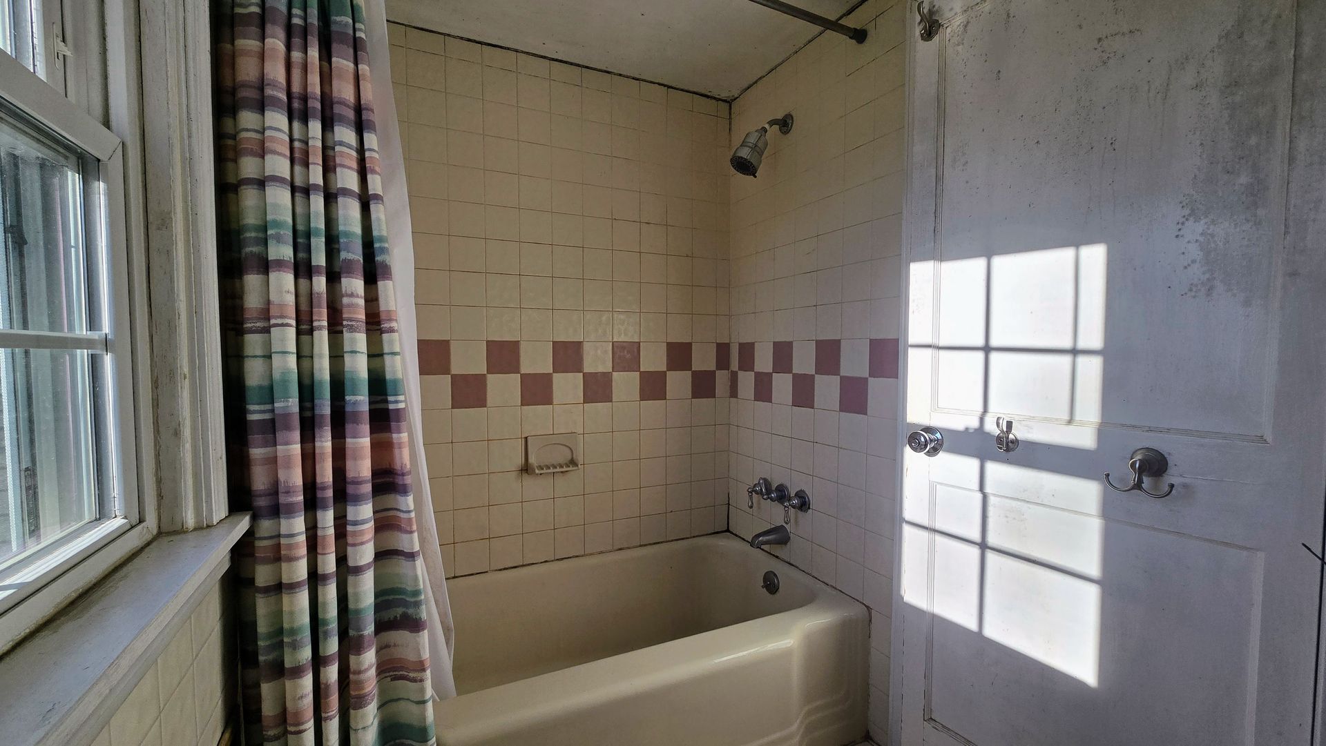 Southington CT Bathroom with a bathtub, shower, checkered tiles, and a window with sunlight.