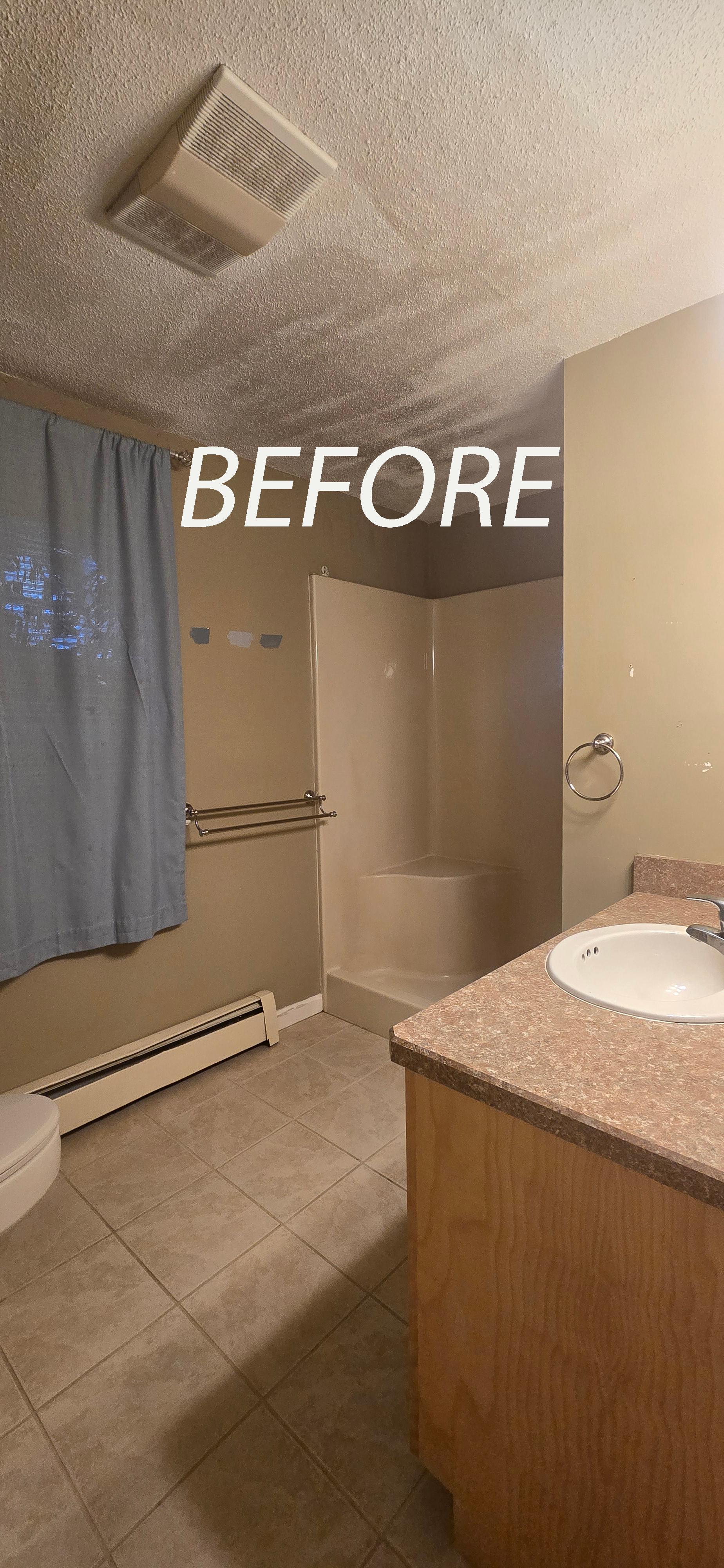 Bathroom with beige walls, shower, vanity, toilet, and a blue curtain. Ceiling is textured with a vent.