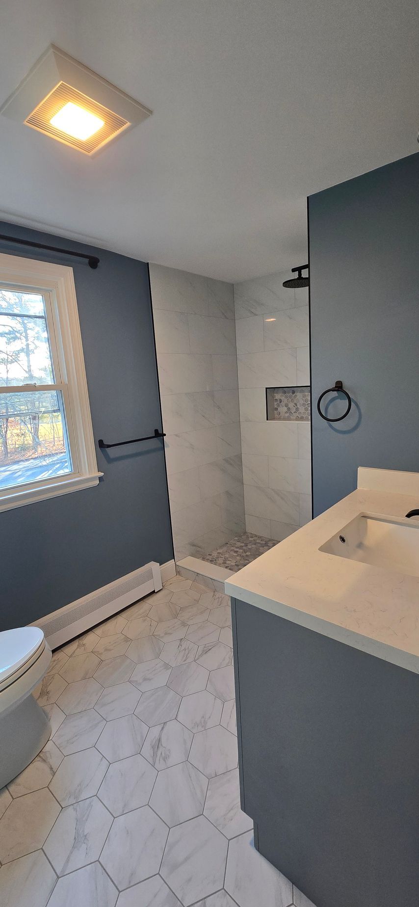 Bristol bathroom with double sinks, large mirror with lightbulbs, and a window.