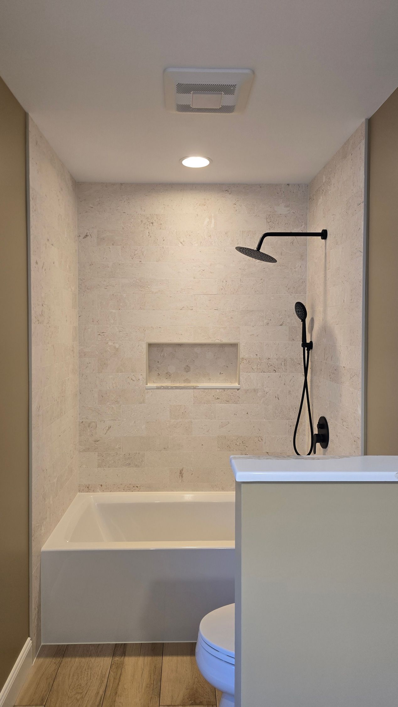 Bathroom in Simsbury, CT completed by First Choice Bathroom Remodeling with black vanity, marble floor, peach walls, and a freestanding tub.