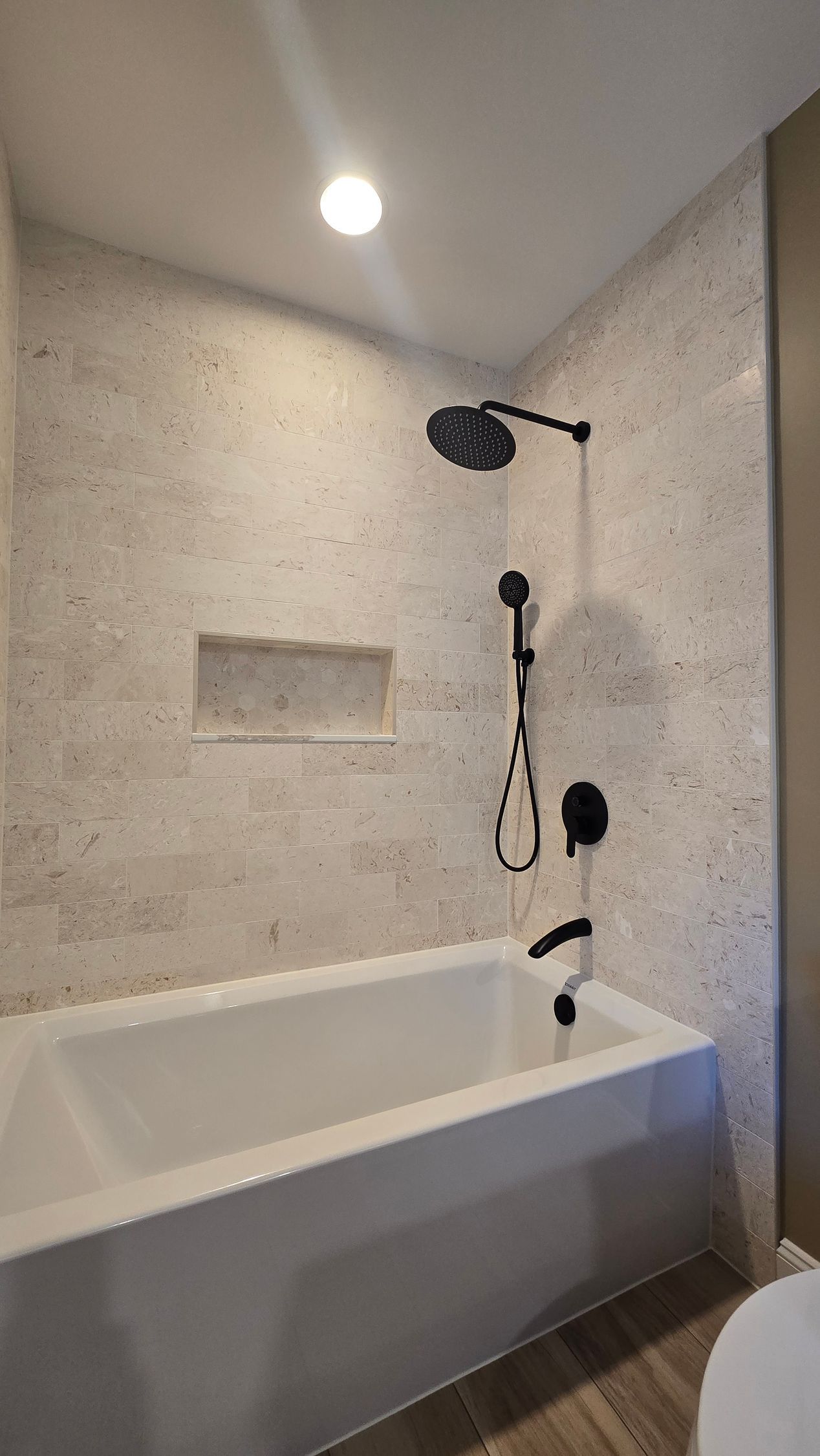Modern bathroom renovation in Wolcott, CT with dark green vanity, glass shower enclosure, and gray patterned rug.