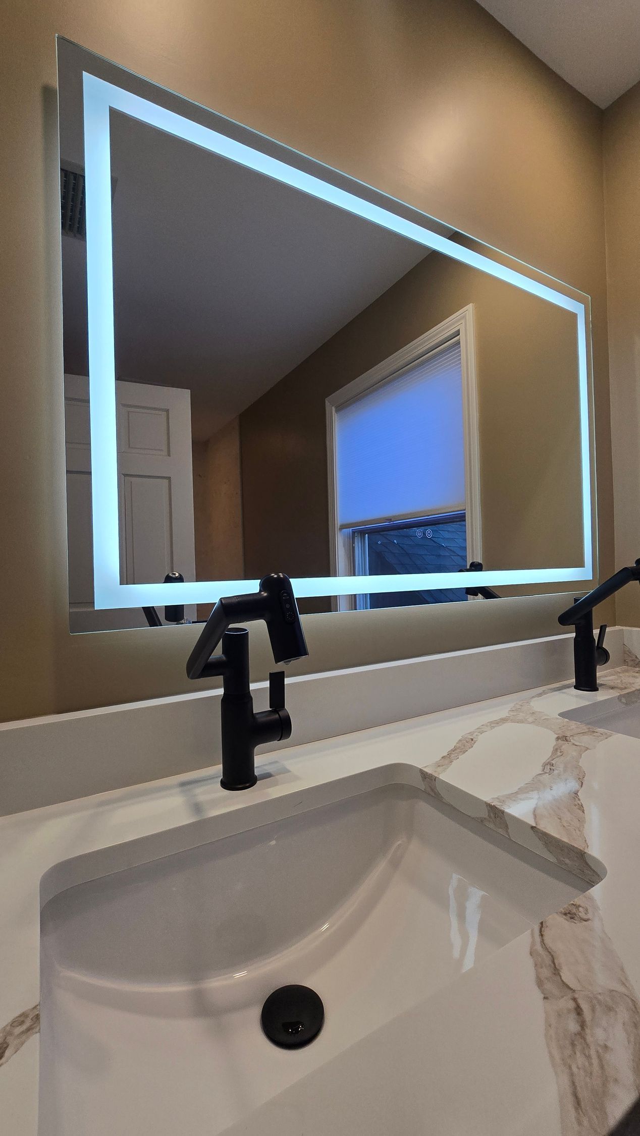 Bristol bathroom with large, illuminated mirror over a white countertop, black faucets, and a sink.
