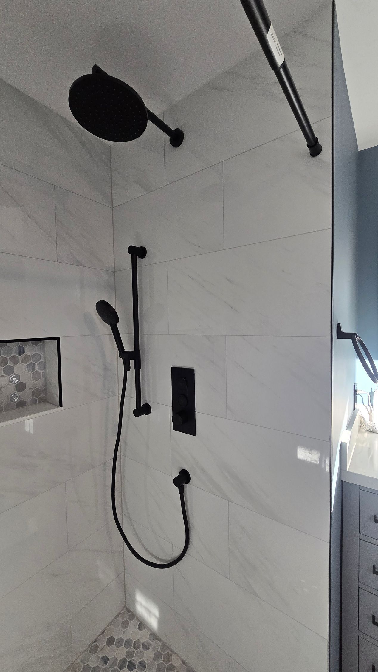 Bristol bathroom with white tub, stone tile walls, black shower fixtures, and a recessed shelf.